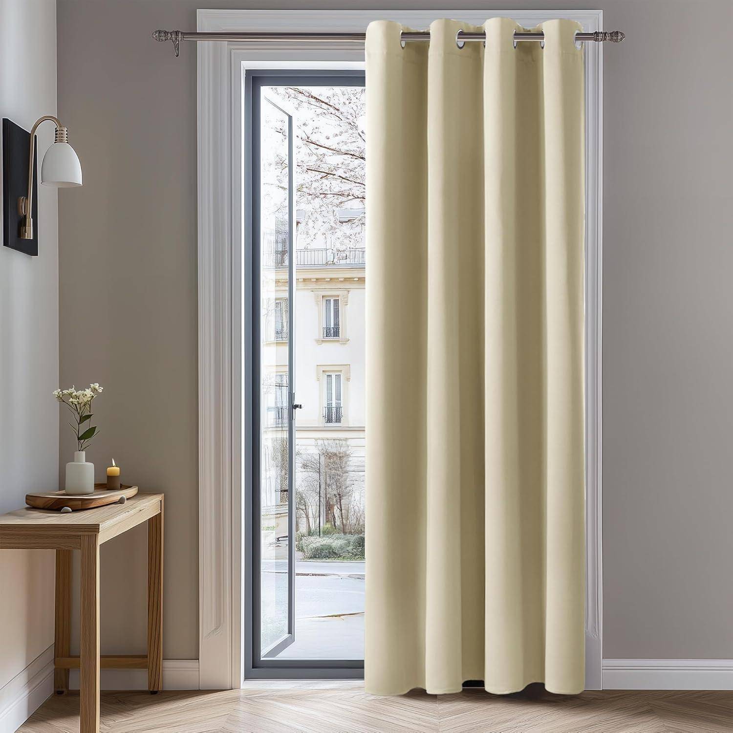 Ein Raum mit einer hohen offenen Tür zum Balkon, cremefarbenen Vorhängen, einem kleinen Holztisch mit einer Vase voller Blumen und einer Wandlampe.