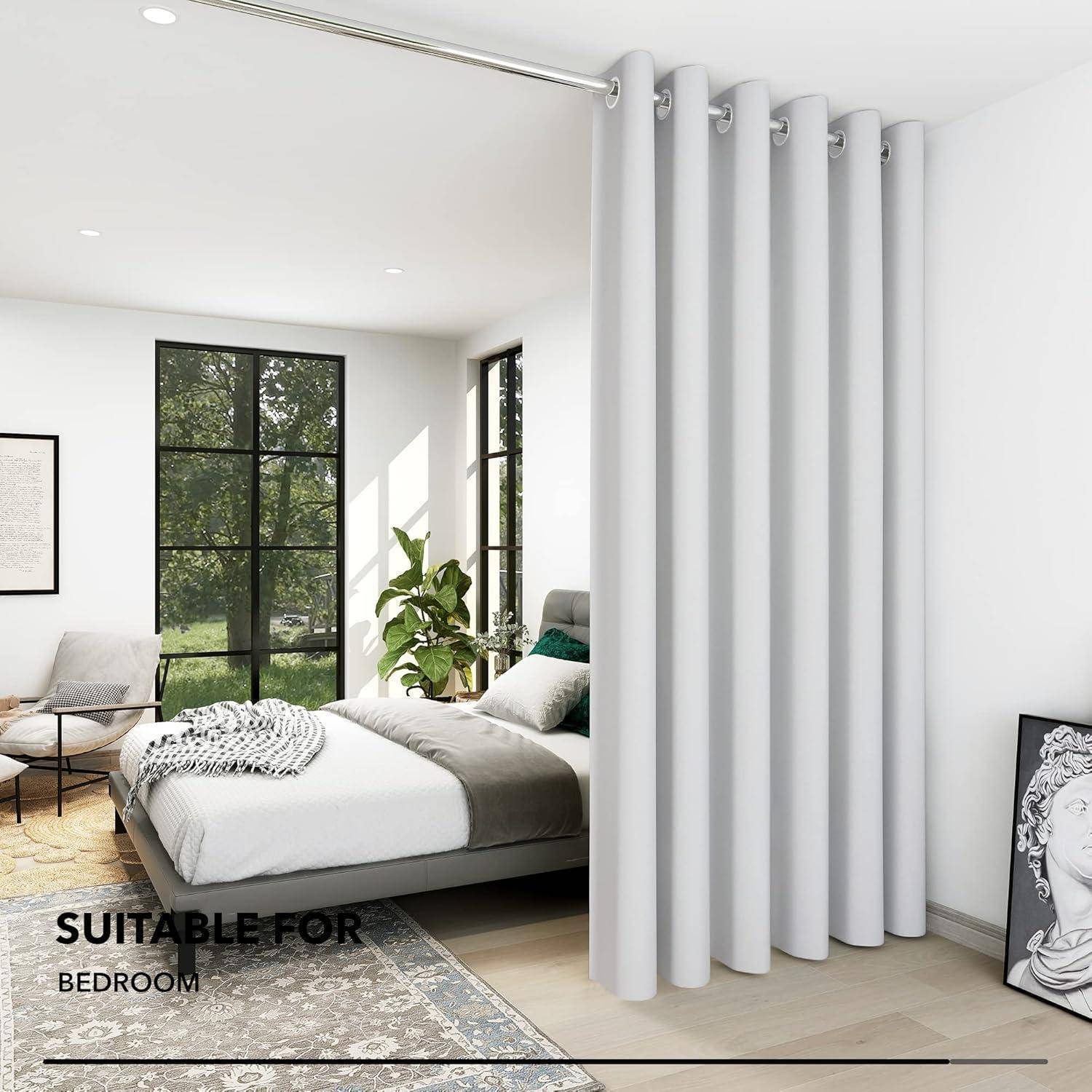 Modernes Schlafzimmer mit einem weißen Bett, einer grünen Pflanze am Fenster und grauen Vorhängen. Text lautet 'FÜR SCHLAFZIMMER GEEIGNET'. Helles natürliches Licht durchflutet den Raum.