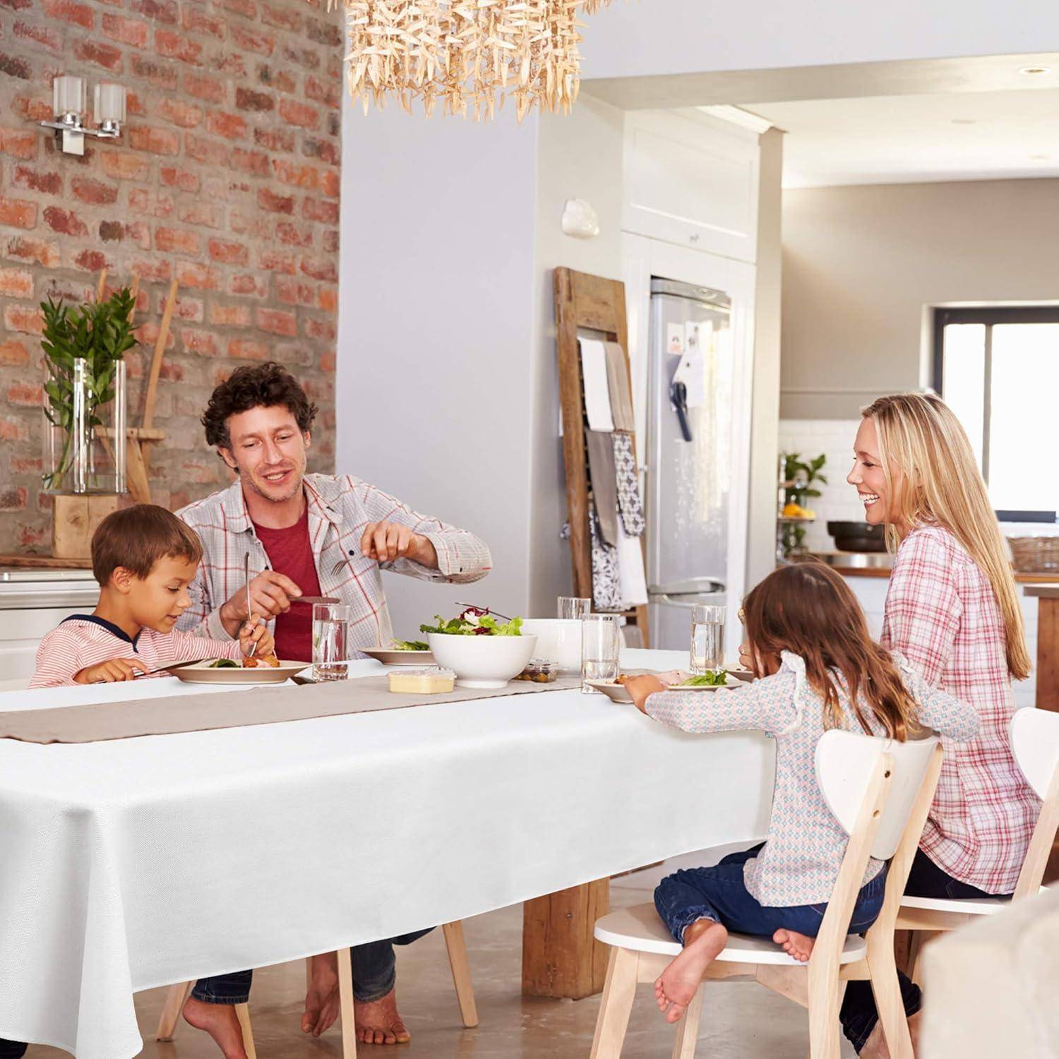 Eine Familie mit vier Personen sitzt an einem Esstisch und teilt eine Mahlzeit in einer hellen, modernen Küche. Die Atmosphäre ist warm und entspannt.