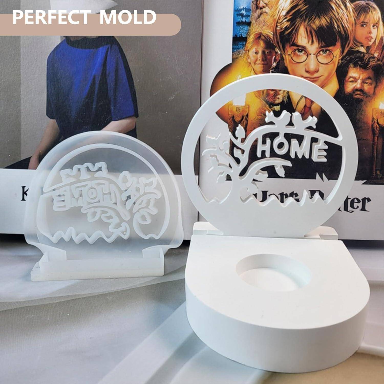 Zwei weiße, runde Formen mit ausgeschnittenen 'Home'-Designs, die vor zwei gerahmten Postern eines Kindes mit Brille platziert sind.