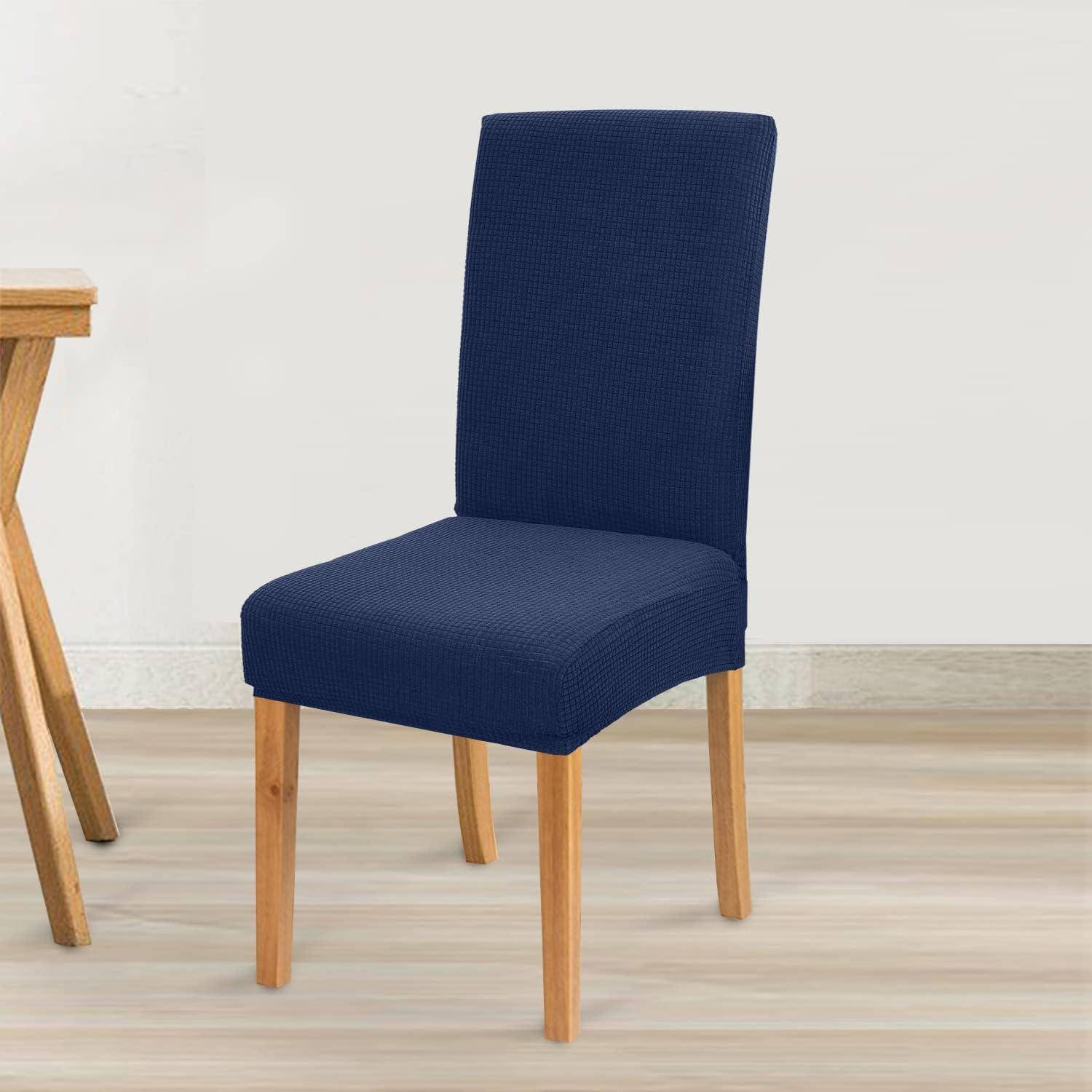 Ein marineblau gepolsterter Essstuhl mit Holzbeinen, der neben einem Holztisch auf einem Holzboden in einem minimalistischen Raum steht.
