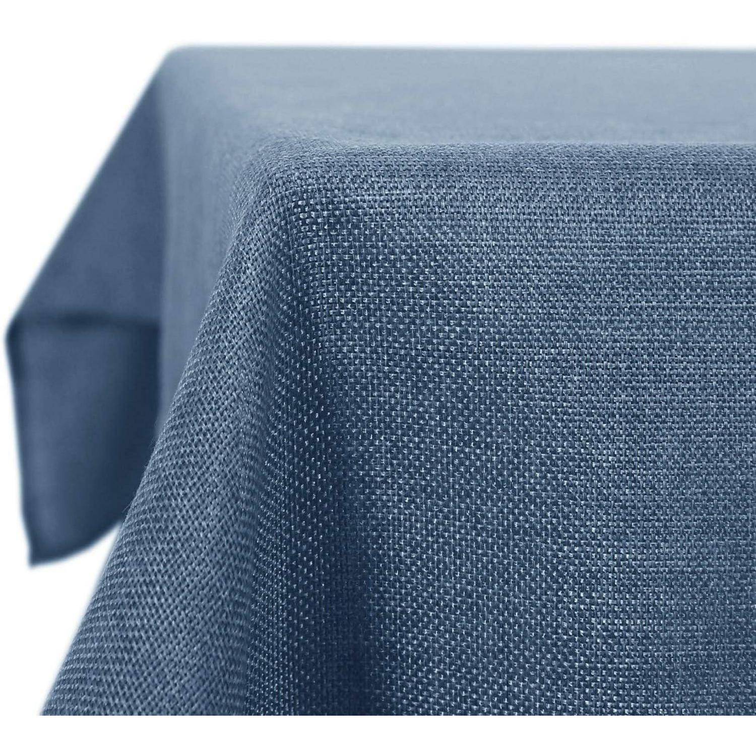 Eine Nahaufnahme eines strukturierten, blauen Tischtuchs, das über einem Tisch drapiert ist und dessen gewebtes Stoffmuster zu sehen ist.