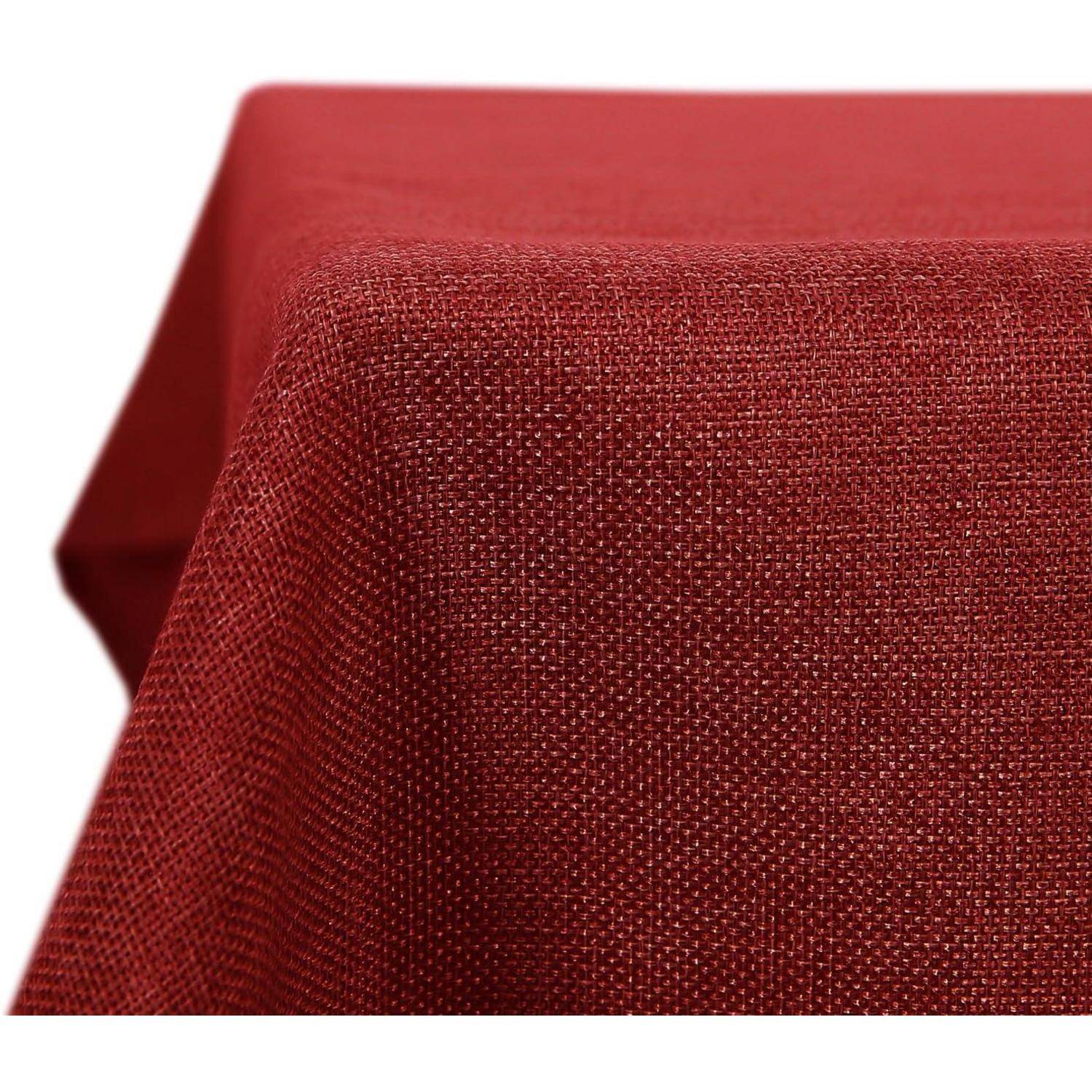 Ein strukturiertes rotes Tischdeckchen, das über eine Ecke eines rechteckigen Tisches drapiert ist und das gewebte Gewebedetail und seine reiche Farbe zur Schau stellt.