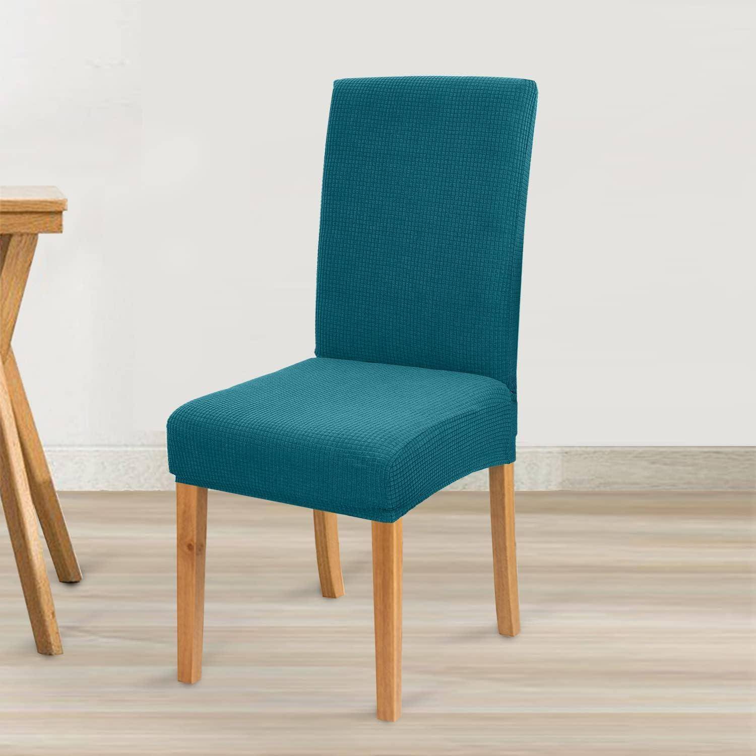 Ein Holzstuhl mit einer blauen Stoffbezug steht auf einem Holzboden neben einem Tisch, an einer weißen Wand.