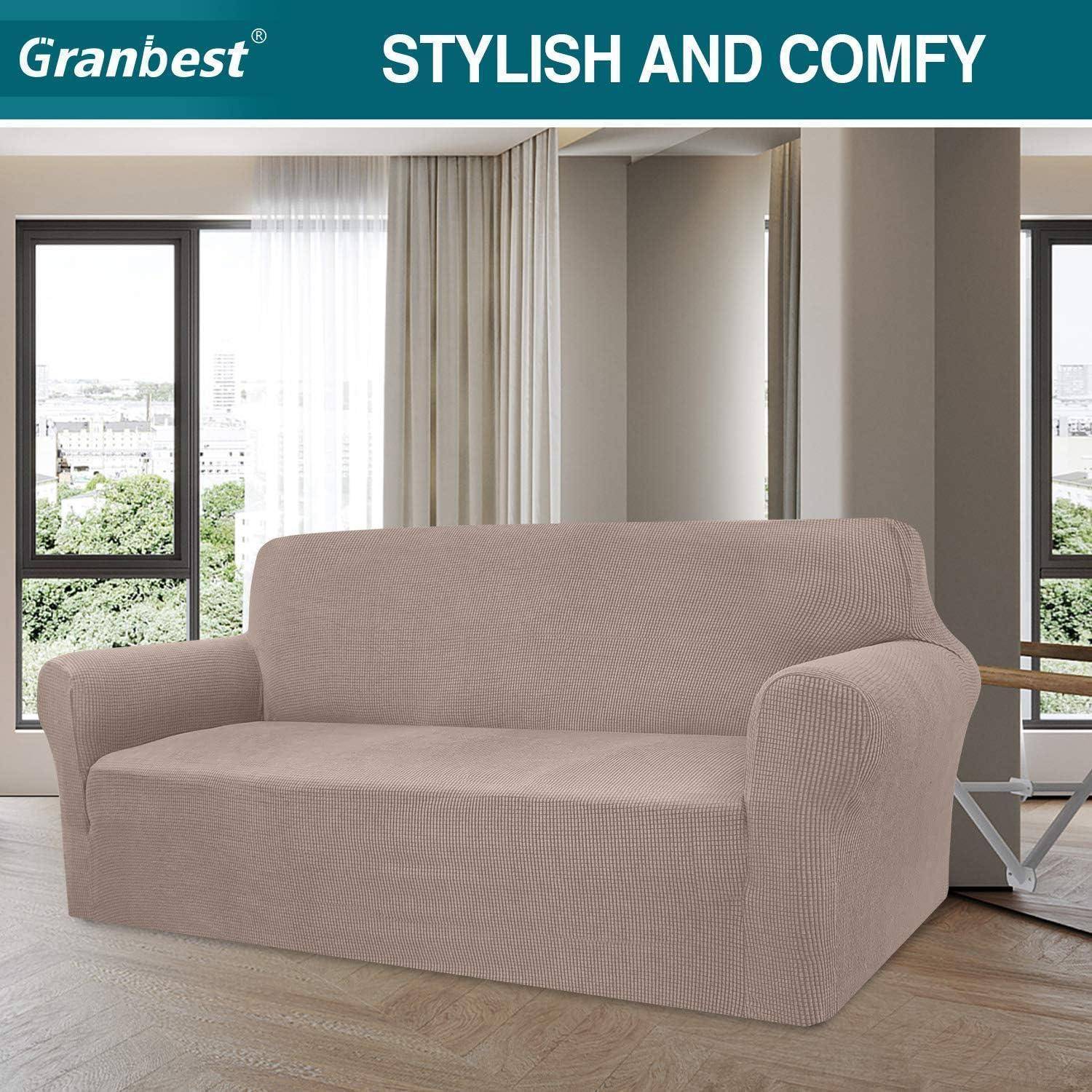 Ein beiger Sofa ist mit einem strukturierten Überwurf in einem hellen Wohnzimmer mit großen Fenstern bedeckt.