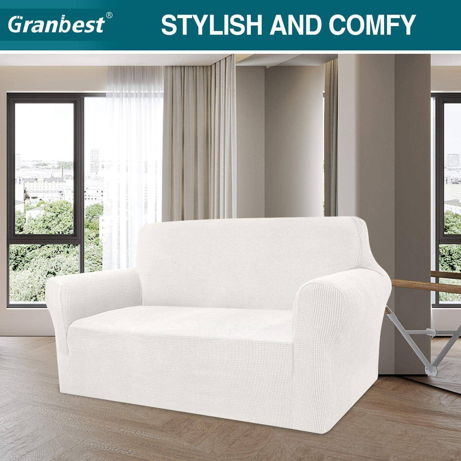Ein weißes Zweisitzer-Sofa mit strukturiertem Bezug steht in einem modernen Wohnzimmer mit großen Fenstern und beigen Vorhängen. Der Text oben lautet: „Stilvoll und gemütlich