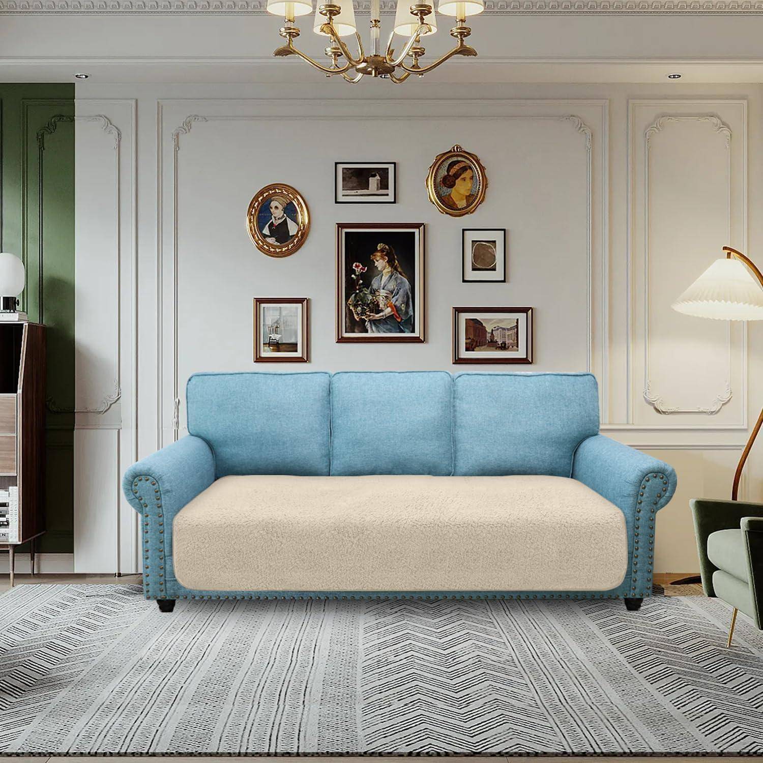 Ein blau-beiger Sofa steht in einem Wohnzimmer mit klassisch gerahmter Kunst an der Wand, einem Kronleuchter und einem gemusterten Teppich.
