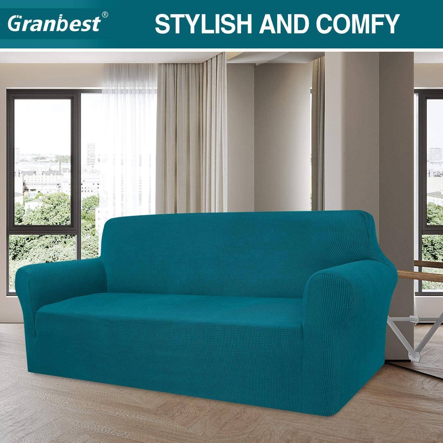 Ein Petrolblau-Sofa mit einem maßgeschneiderten Überzug steht in einem modernen Wohnzimmer mit großen Fenstern und leichten Vorhängen. Der Text darüber lautet "Stilvoll und gemütlich"".
