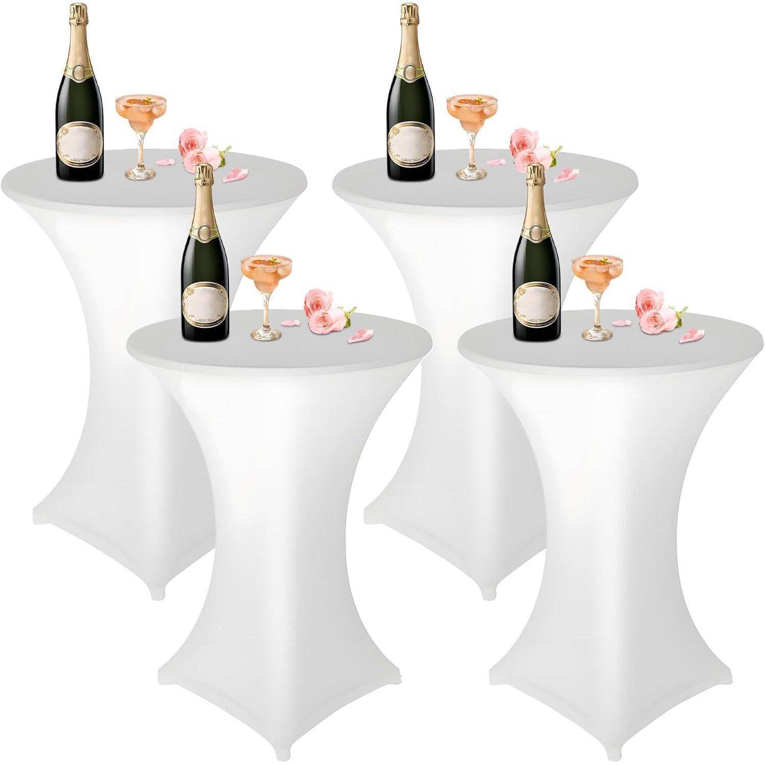 Vier hohe weiße Cocktailtische, auf denen jeweils Champagnerflaschen, mit Champagner gefüllte Coupe-Gläser und rosa Blumen arrangiert sind.