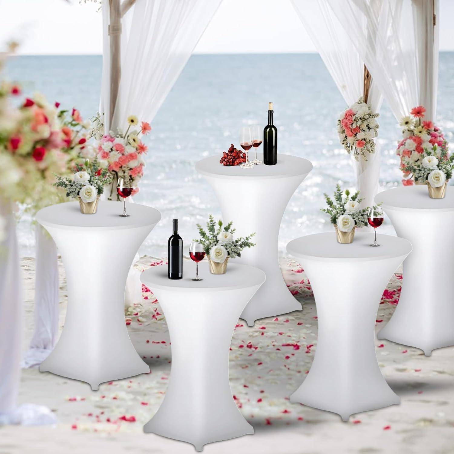 Weiße Tische mit roten Blumen, Weinflaschen und Gläsern sind am Strand unter einem Baldachin aufgestellt, mit Blick auf das Meer.