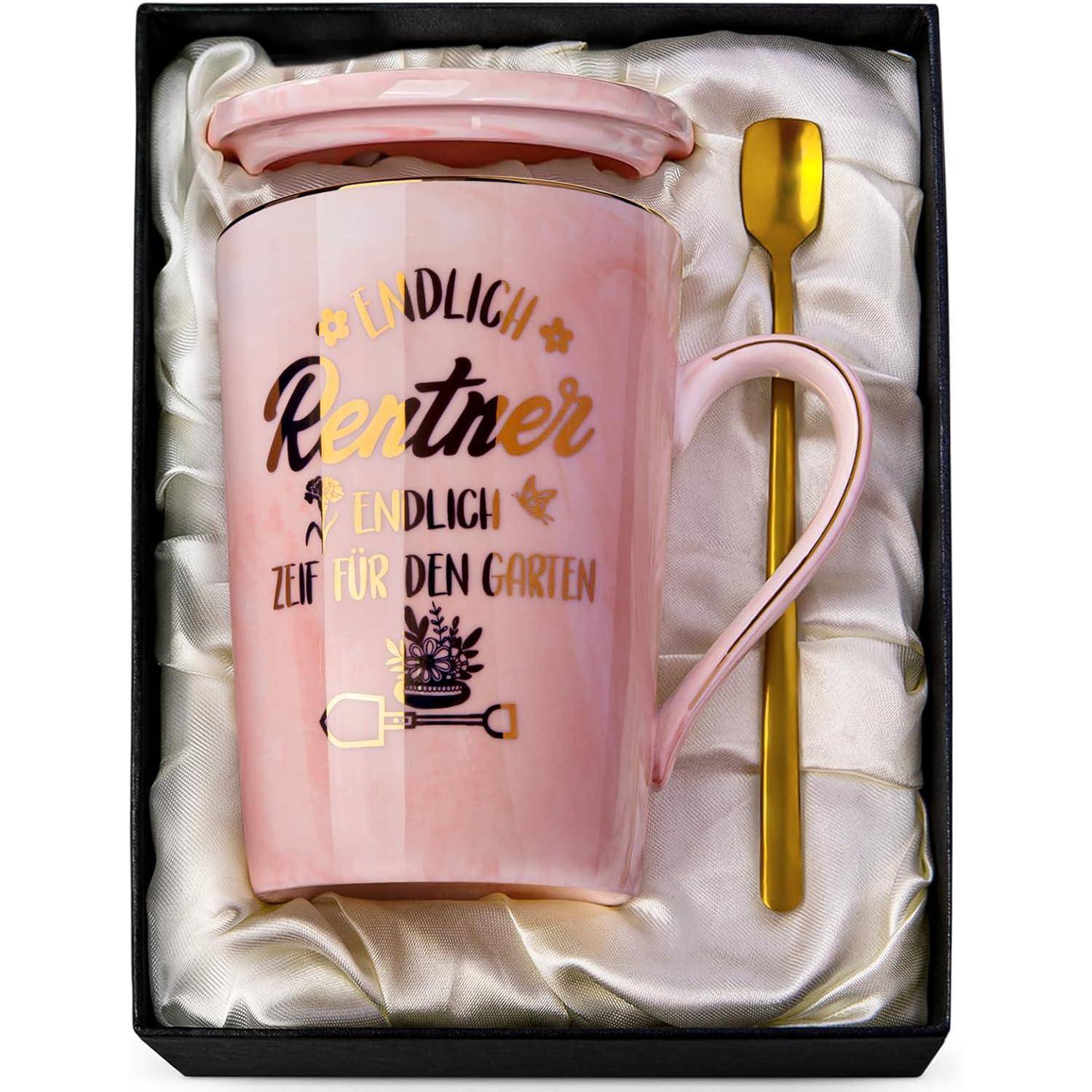 Rosa Keramiktasse mit deutschem Text 'Endlich Rentner - Endlich Zeit für den Garten', versehen mit Gartenmotiven, begleitet von einem goldfarbenen Metalllöffel, in einer satinausgekleideten Box.