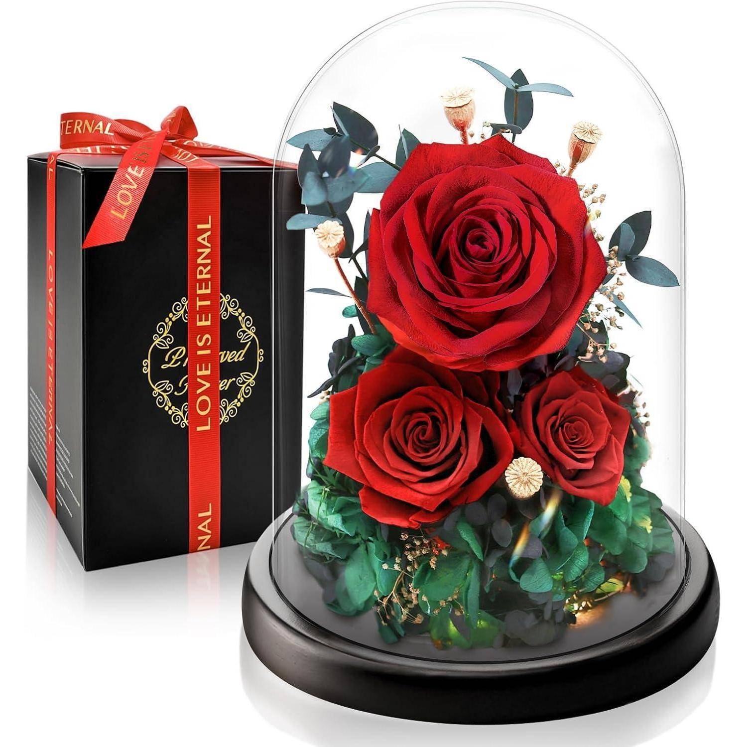 Glaskuppel mit drei roten Rosen und Grünpflanzen; daneben befindet sich eine Geschenkbox mit dem Text 'LIEBE IST EWIG' auf dem Band.
