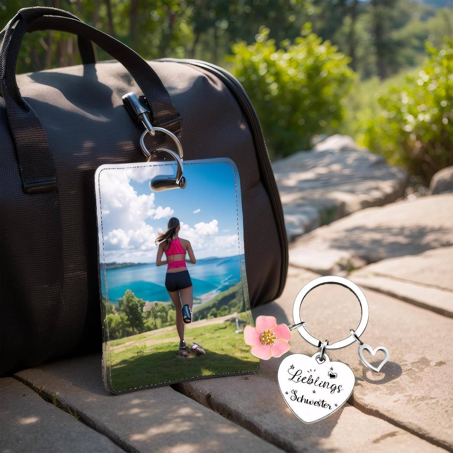 Eine Sporttasche steht im Freien mit einem Schlüsselanhänger, auf dem ein Foto von einer Person zu sehen ist, die auf einen See und Berge zuläuft. Der Schlüsselanhänger trägt die Aufschrift 