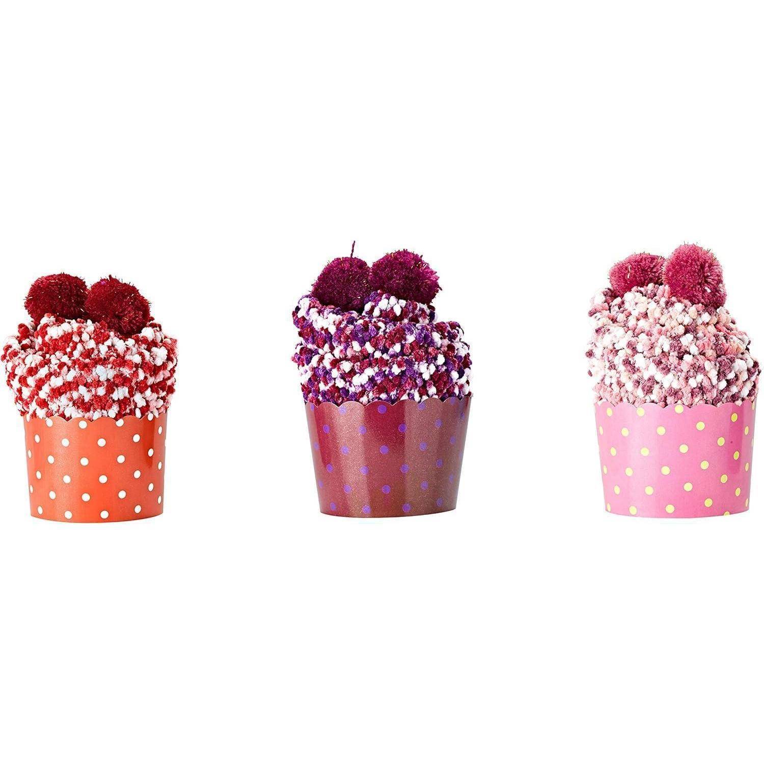 Drei farbenfrohe Bommelmützen in Rot, Lila und Rosa liegen nebeneinander, wobei jede Mütze ein Polka-Dot-Muster am Rand hat.