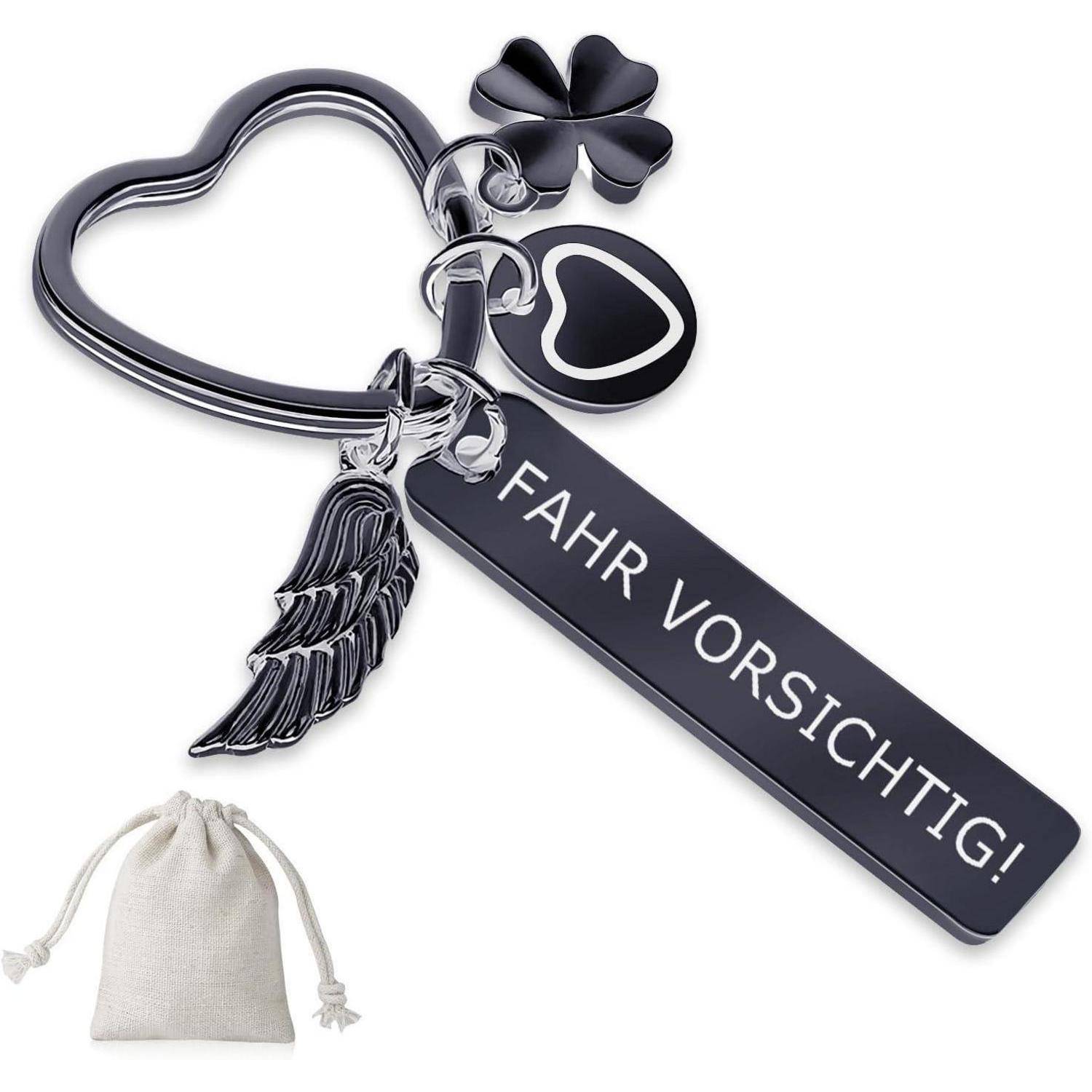Schlüsselanhänger mit der Aufschrift ‚Fahr vorsichtig!', der einen Herzrahmen, einen Kleeblatt-Anhänger, einen Herz-Charm und einen Flügel enthält, mit einem kleinen Zugbeutel darunter.