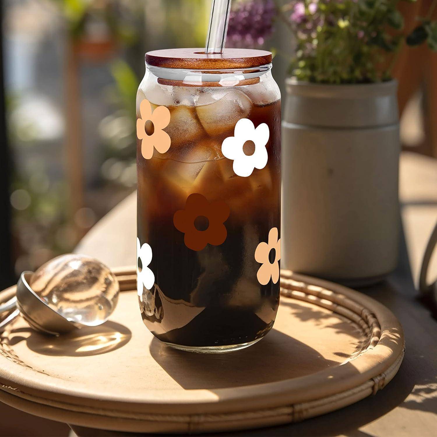 Eine Glasstunde Eiskaffee mit Blumendekoration am Glas steht auf einem Holztablett, begleitet von einem Glas, in einer sonnendurchfluteten Umgebung.