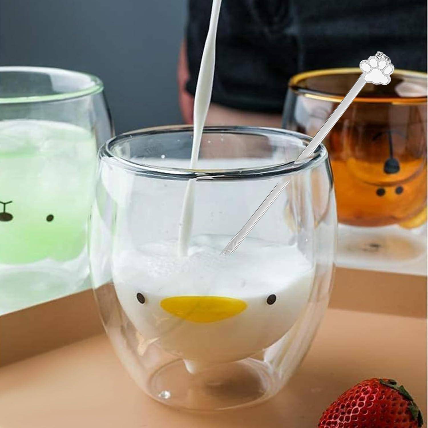 Drei Gläser mit Tiermotiven und Getränken; das mittlere Glas zeigt ein weißes Bärengesicht mit einem Strohhalm. Eine Erdbeere liegt in der Nähe auf dem Tisch.