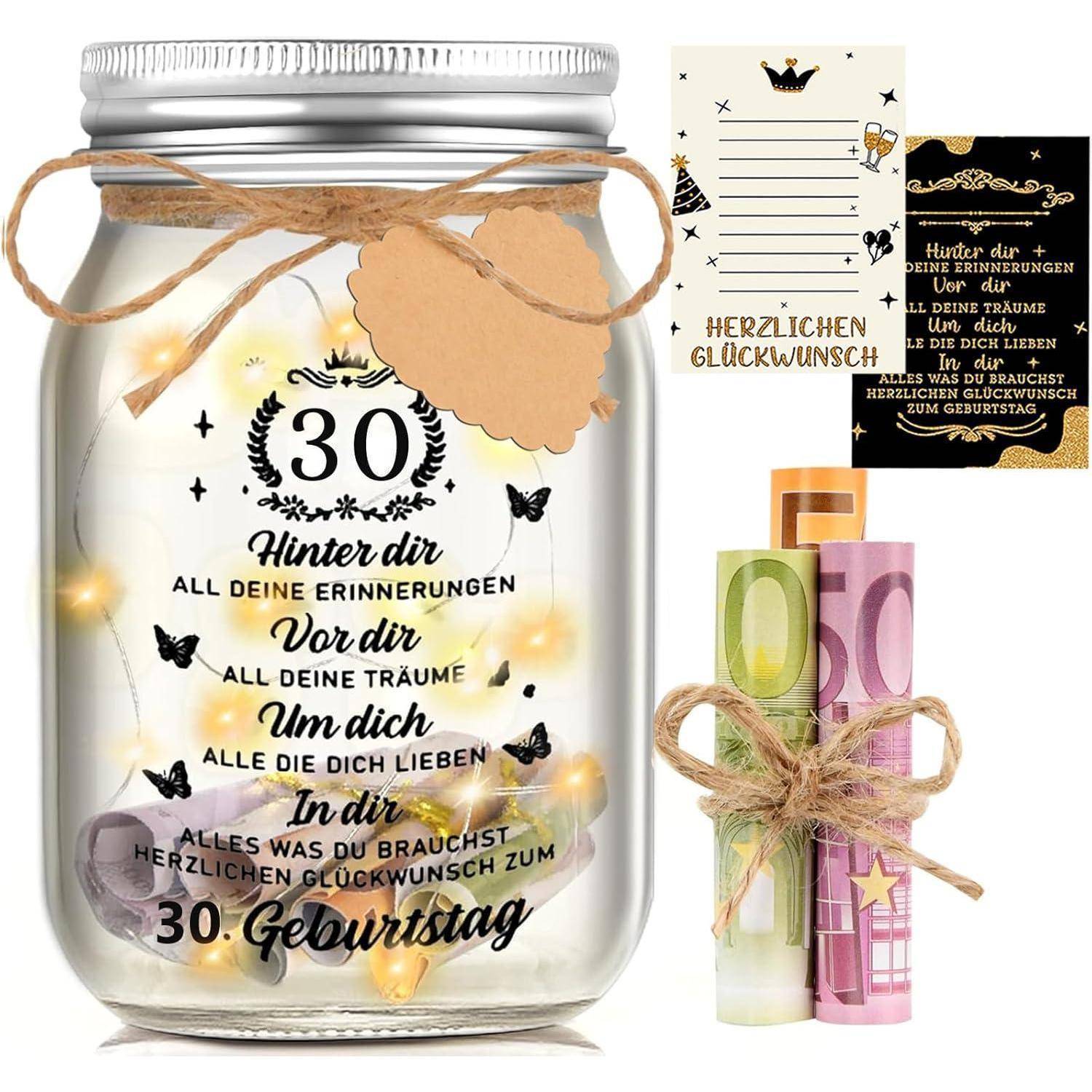 Ein Einmachglas mit Lichterketten und deutschem Text zur Feier des 30. Geburtstags, begleitet von dekorativen Karten und Papierrollen.
