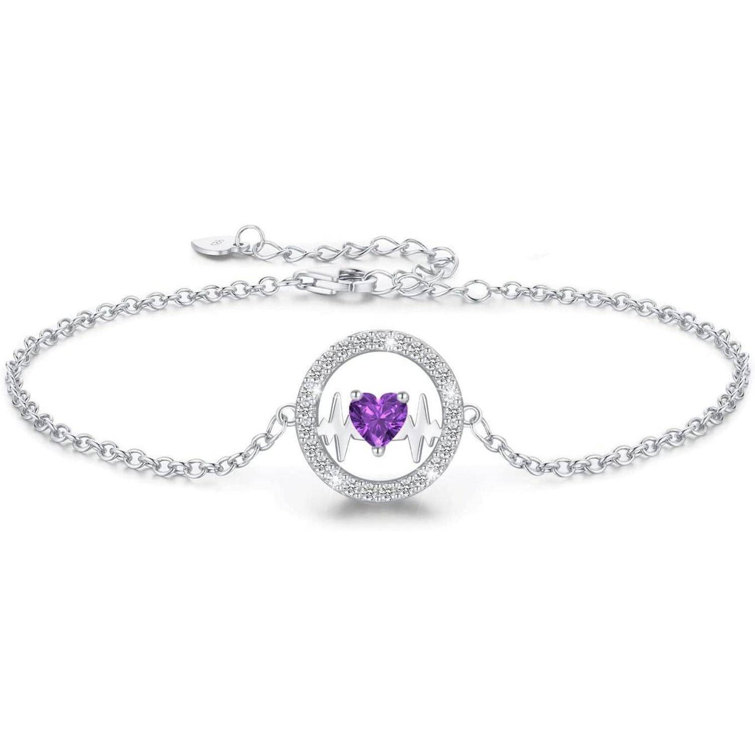 Ein silbernes Armband mit einem runden Anhänger, der einen lila herzförmigen Edelstein zeigt, der von zwei Händen gehalten wird, umgeben von kleinen transparenten Kristallen.