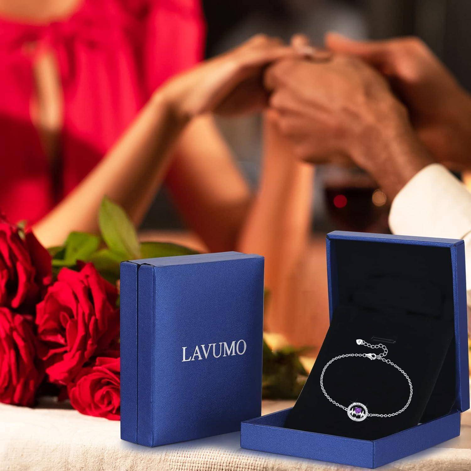 Ein Armband mit einem Anhänger, das in einer geöffneten blauen Schmuckschatulle mit der Aufschrift „LAVUMO