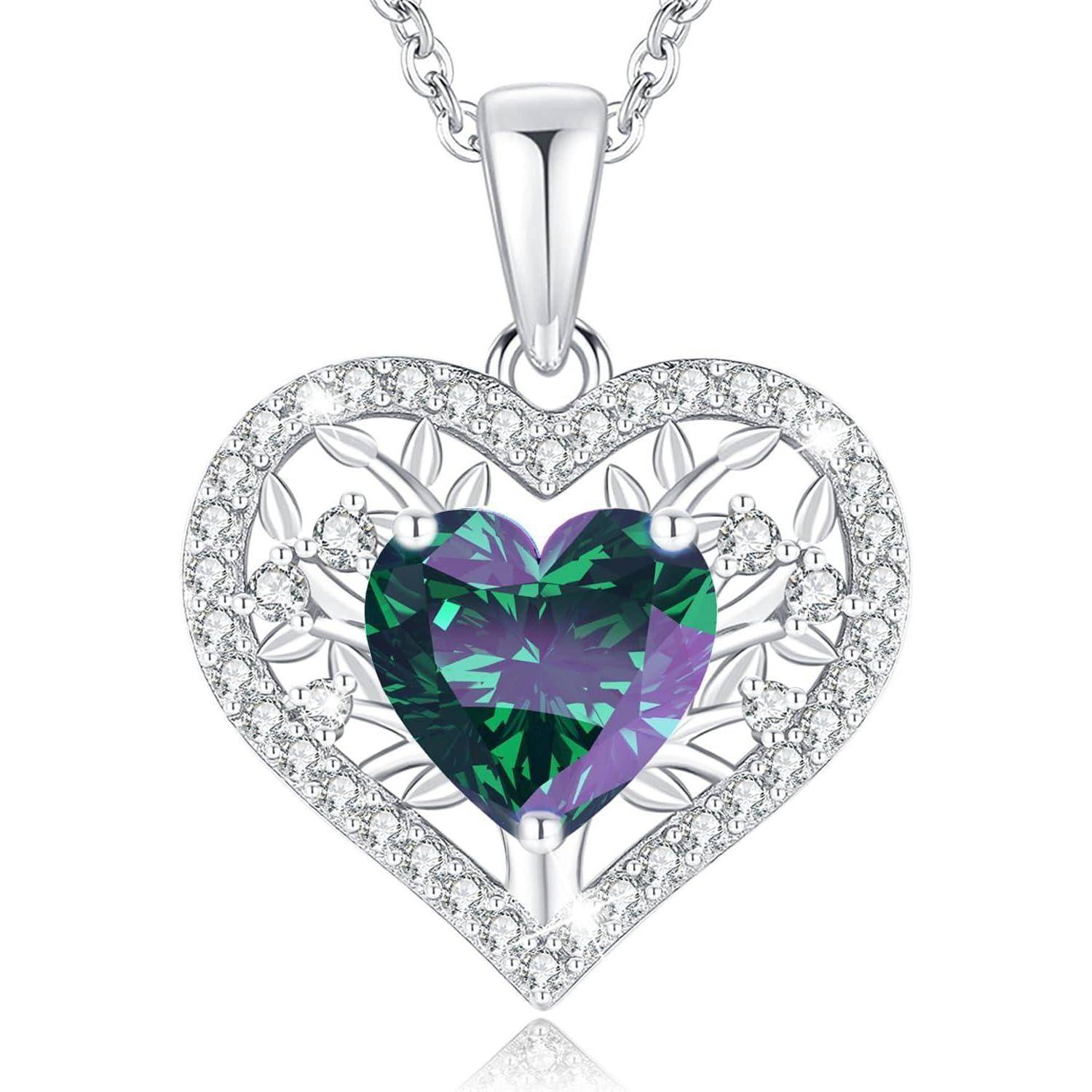 Eine herzförmige Halskette mit einem zentralen grünen Edelstein und umgebendem silbernem Filigran-Design an einer Kette.