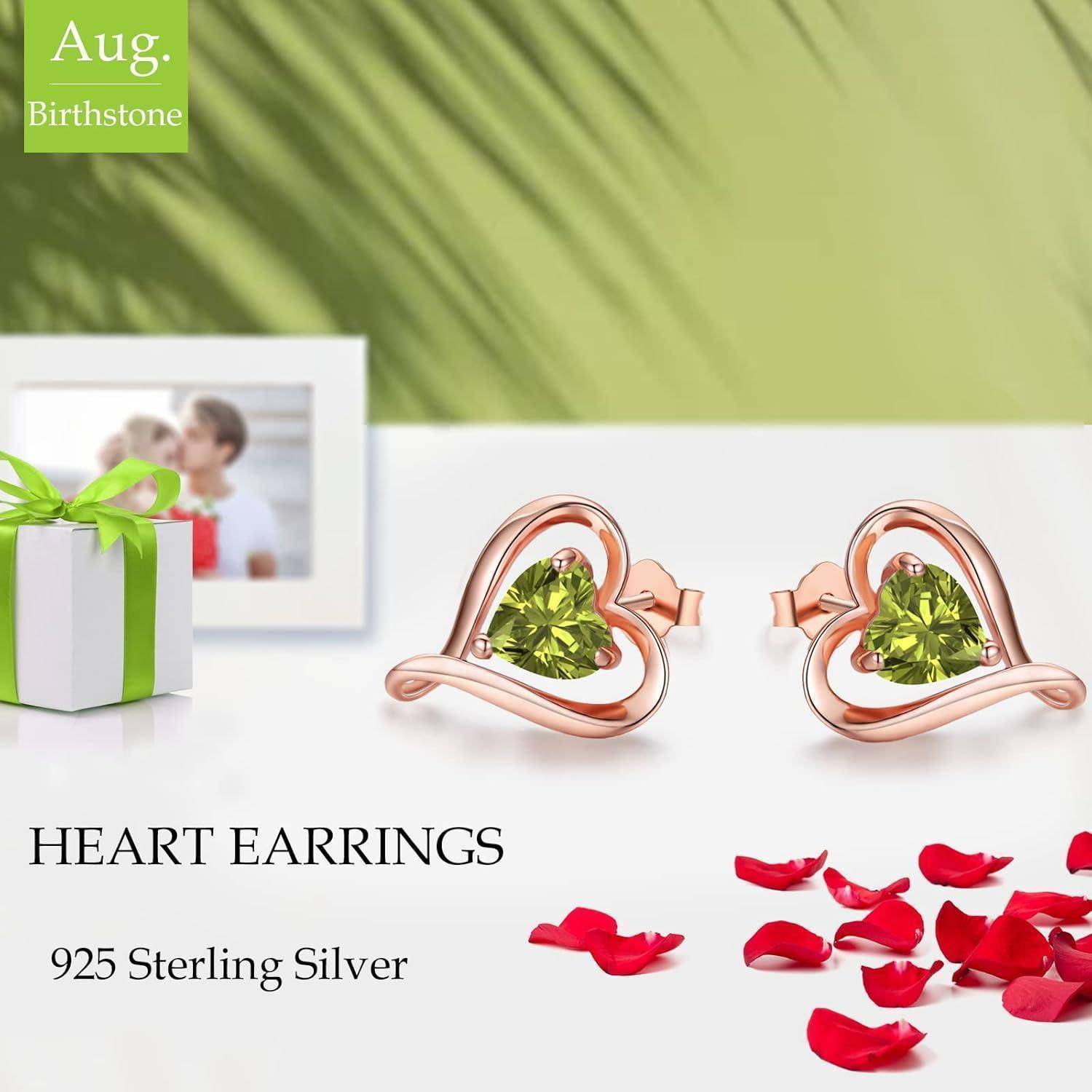 Herzförmige Ohrringe aus Sterlingsilber mit grünen Steinen werden präsentiert. Begleitet von dekorativen roten Blütenblättern und einer kleinen Geschenkbox.