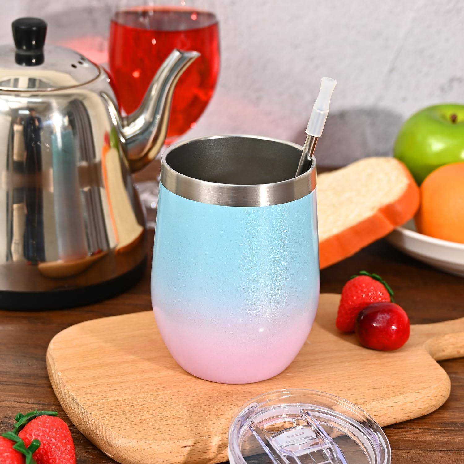 Eine Reisebecher in Blau- und Rosatönen mit einem Strohhalm auf einem Holzbrett, umgeben von Erdbeeren, Brot, einer Kanne und einem Glas Saft.