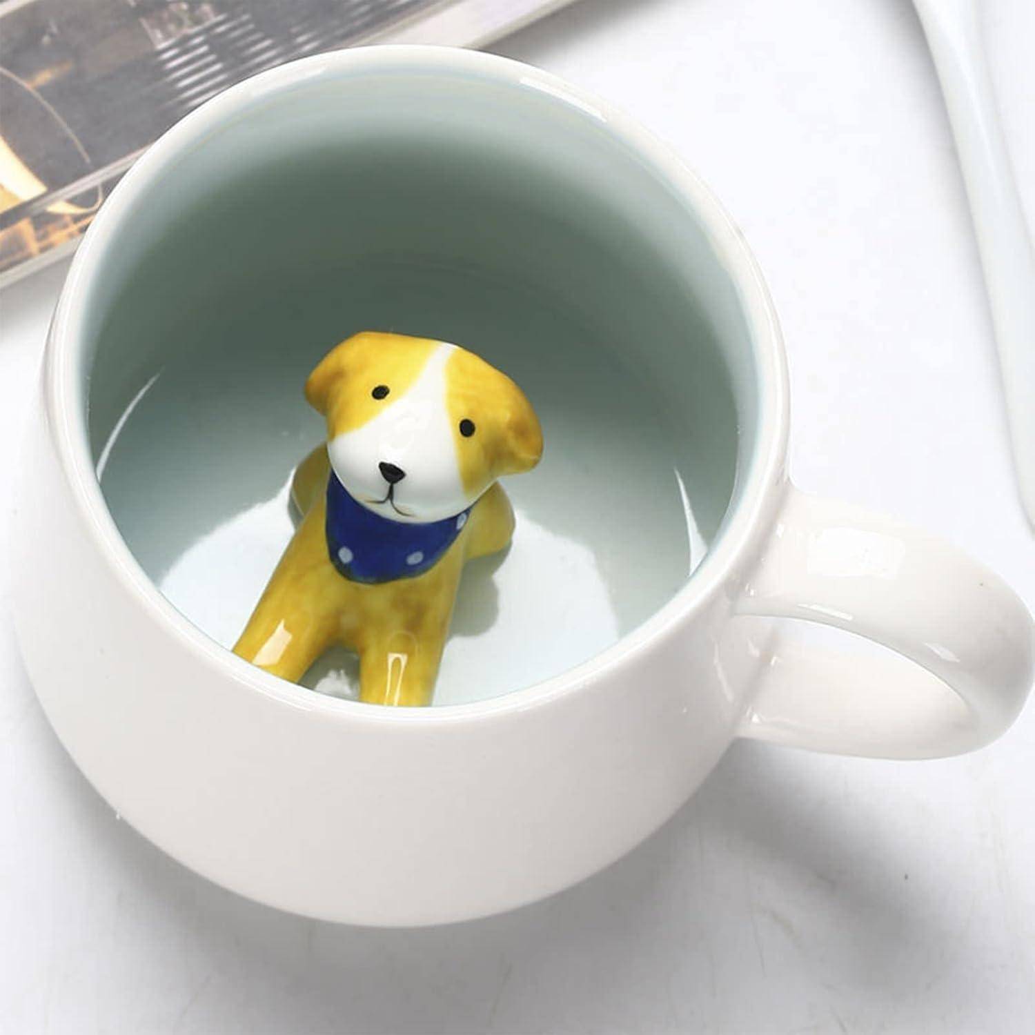 Eine Keramiktasse mit einer niedlichen Hundefigur am Boden, teilweise eingetaucht, die einen blauen Schal trägt, vor einem weißen Hintergrund.