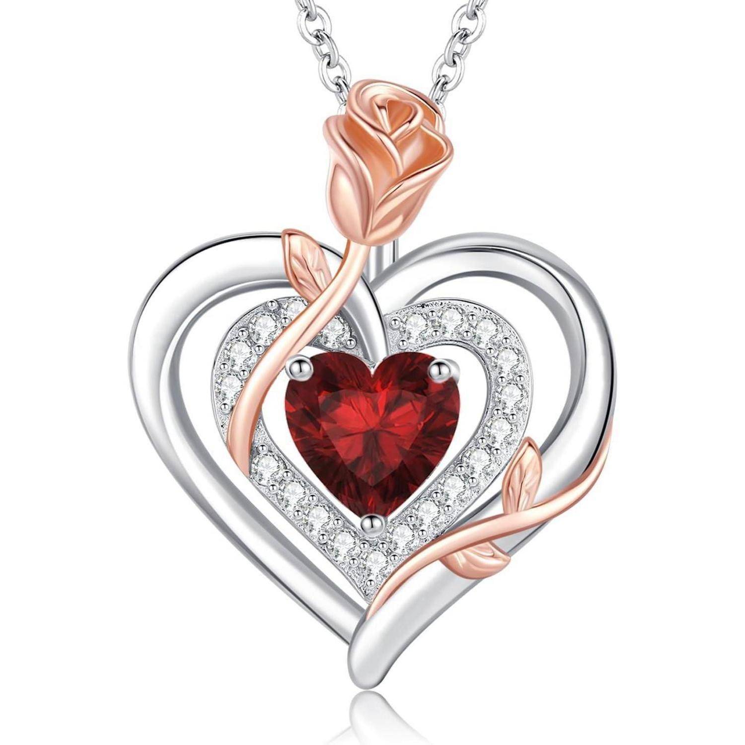 Eine herzförmige Anhänger mit einem roten Edelstein in der Mitte, umrandet von kleinen Diamanten, verwoben mit einem Rosenmotiv aus Roségold an einer Silberkette.