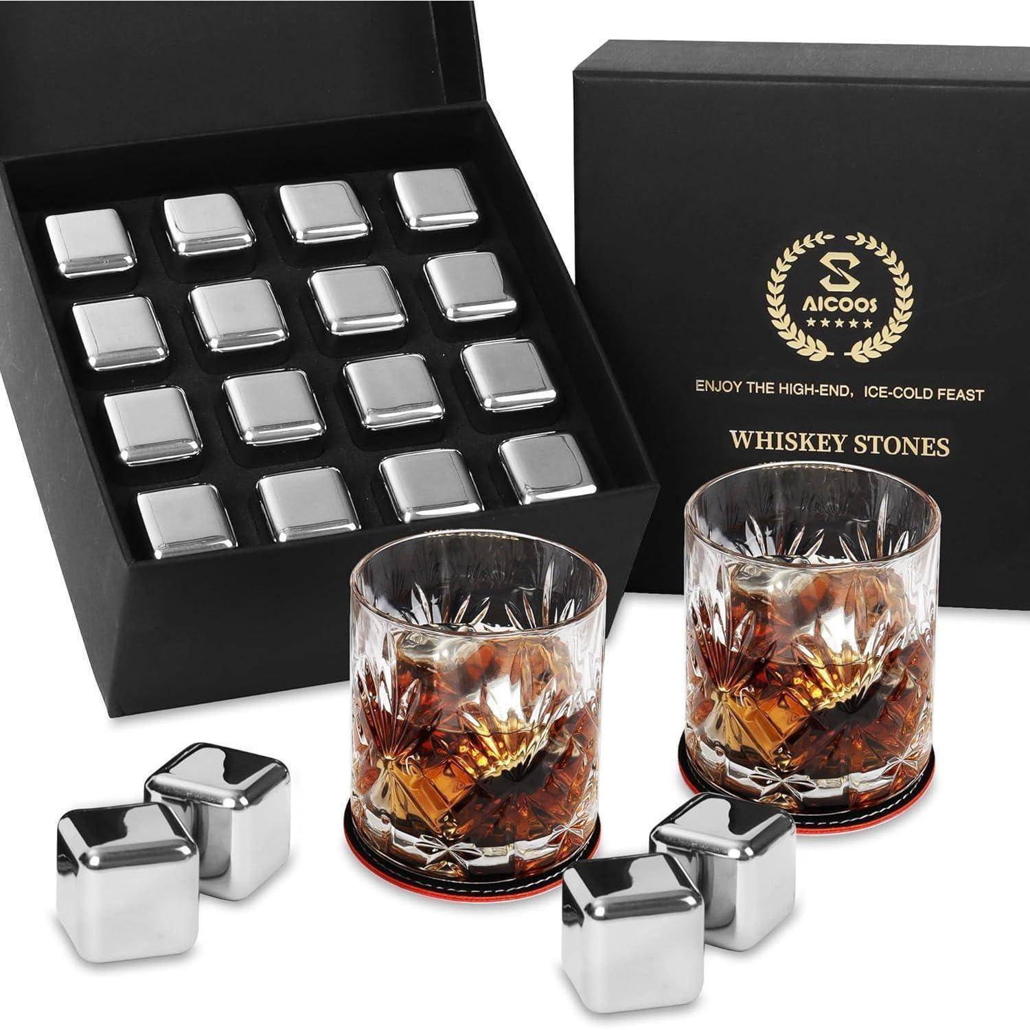 Ein Set aus Edelstahl-Whiskeysteinen und zwei mit Whiskey gefüllten Gläsern, neben einer geöffneten Box. Text lautet: 