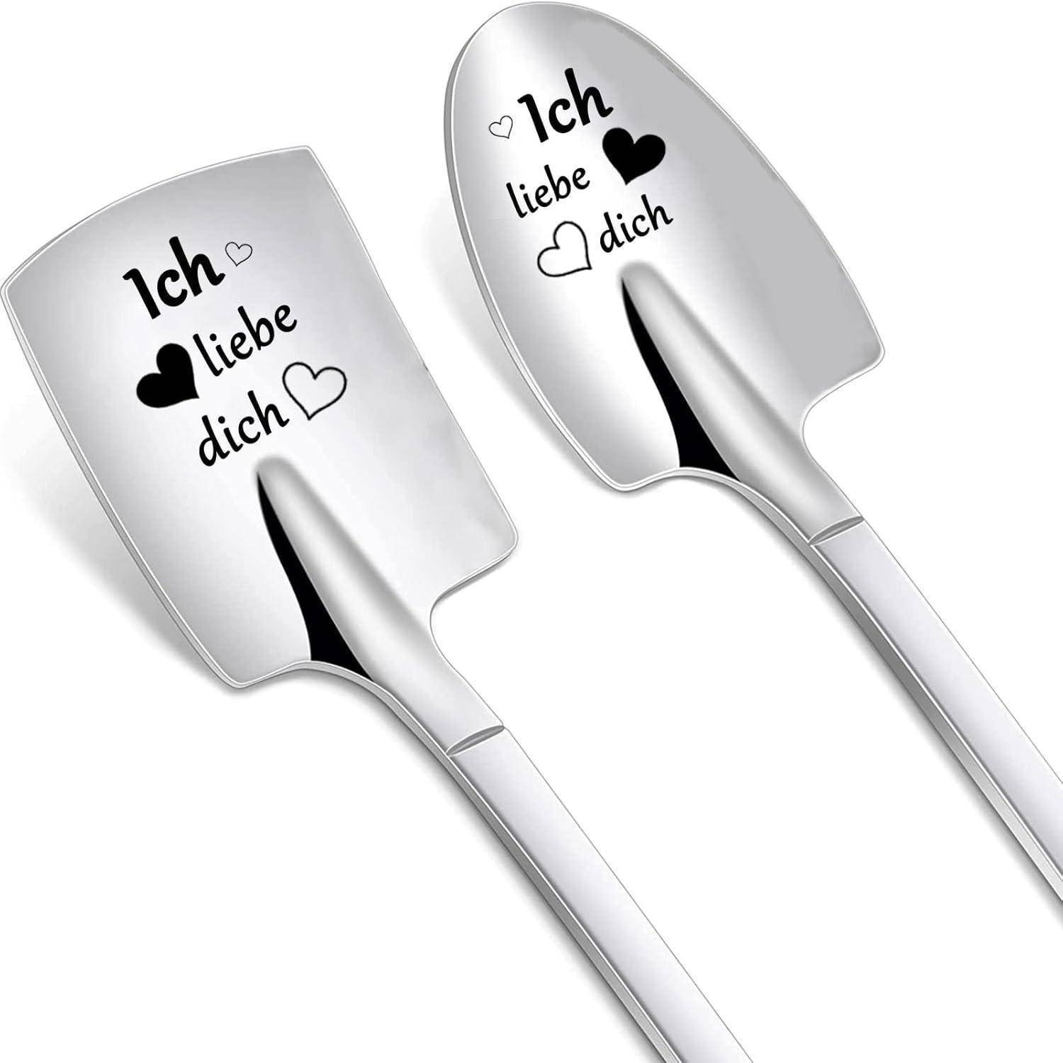 Zwei silberne Schaufeln mit gravierten Wörtern 'Ich liebe dich' und Herzdesigns werden gezeigt, die als romantisches Geschenk verwendet werden und Liebe symbolisieren.
