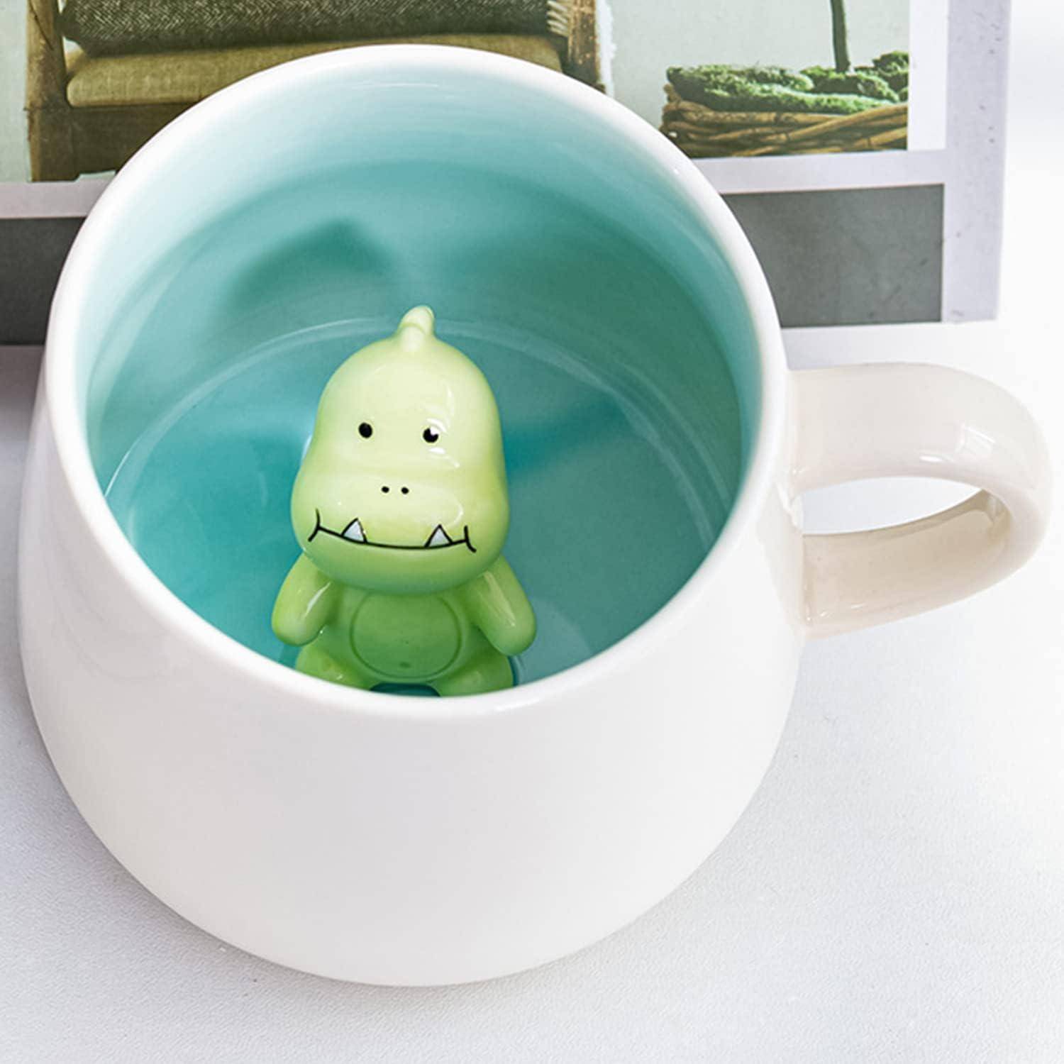 Eine weiße Tasse, gefüllt mit hellblauer Flüssigkeit, in der eine kleine, grüne Dinosaurierfigur bis zum Kopf eingetaucht ist.