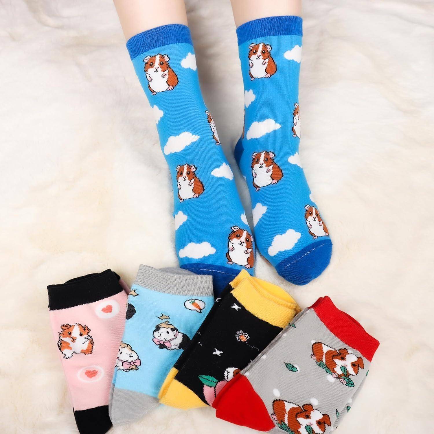 Füße mit blauen Socken, die Meerschweinchen und Wolken zeigen. Zusätzliche Socken darunter: rosa mit Herzen, hellblau, gelb, schwarz und rot mit Mustern.