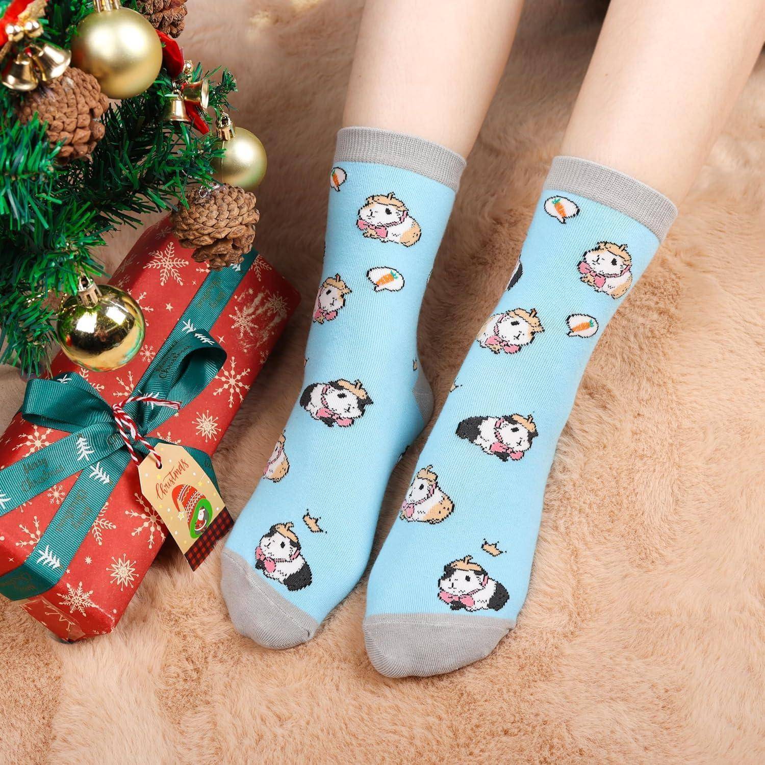 Eine Person trägt blaue Socken mit Cartoontiermotiven und sitzt neben einem eingepackten Geschenk und einem geschmückten Weihnachtsbaum.