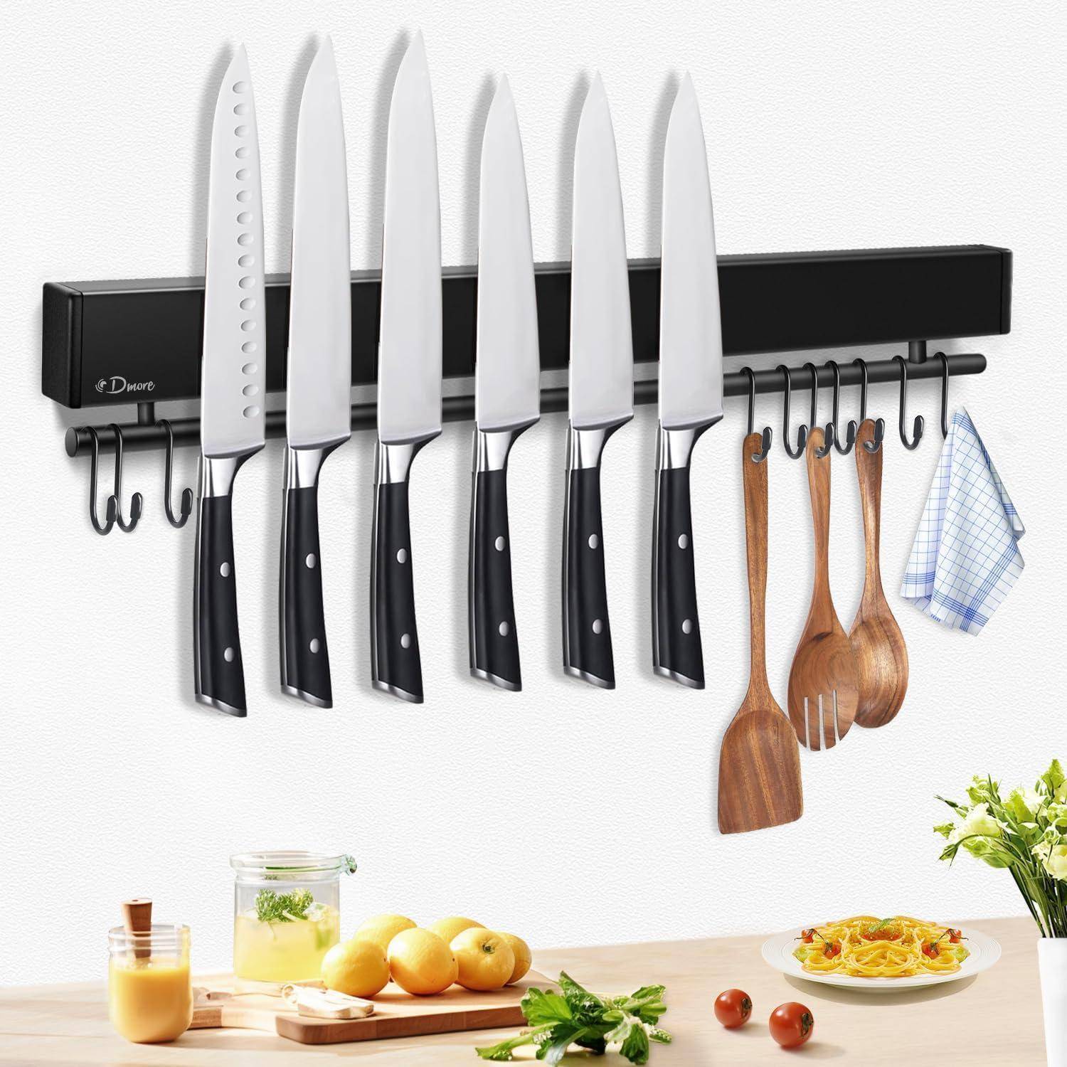 Ein Magnetstreifen an der Küchenwand hält sieben Messer, drei Holzutensilien und ein Handtuch. Darunter liegt ein Schneidebrett mit gehackten Tomaten und einem Zitronenglas auf der Arbeitsplatte.