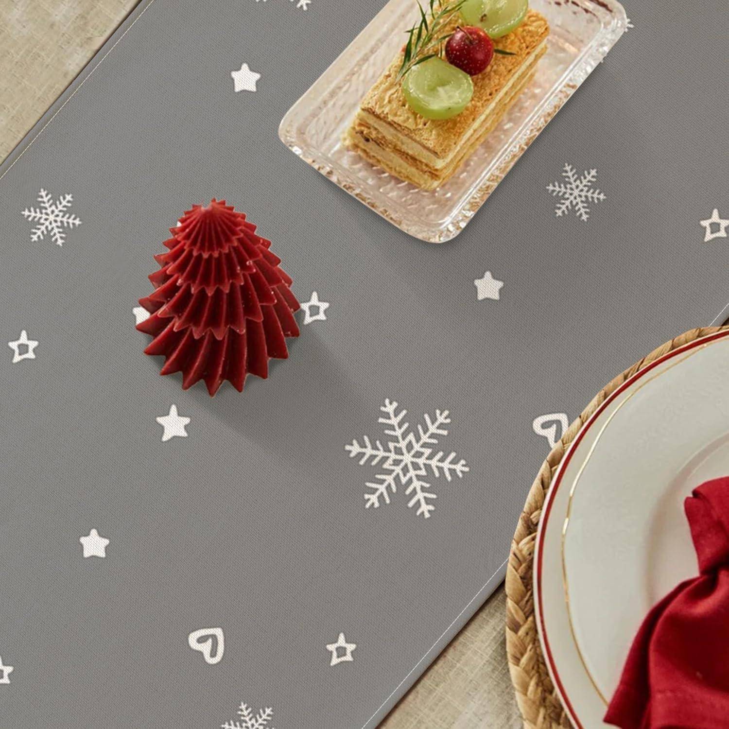 Eine festliche Tischdekoration mit einem roten Papierbaum, einem Teller mit geschichteter Pastete und Beeren, Schneeflocken- und Sterndekoration auf einem grauen Platzset.