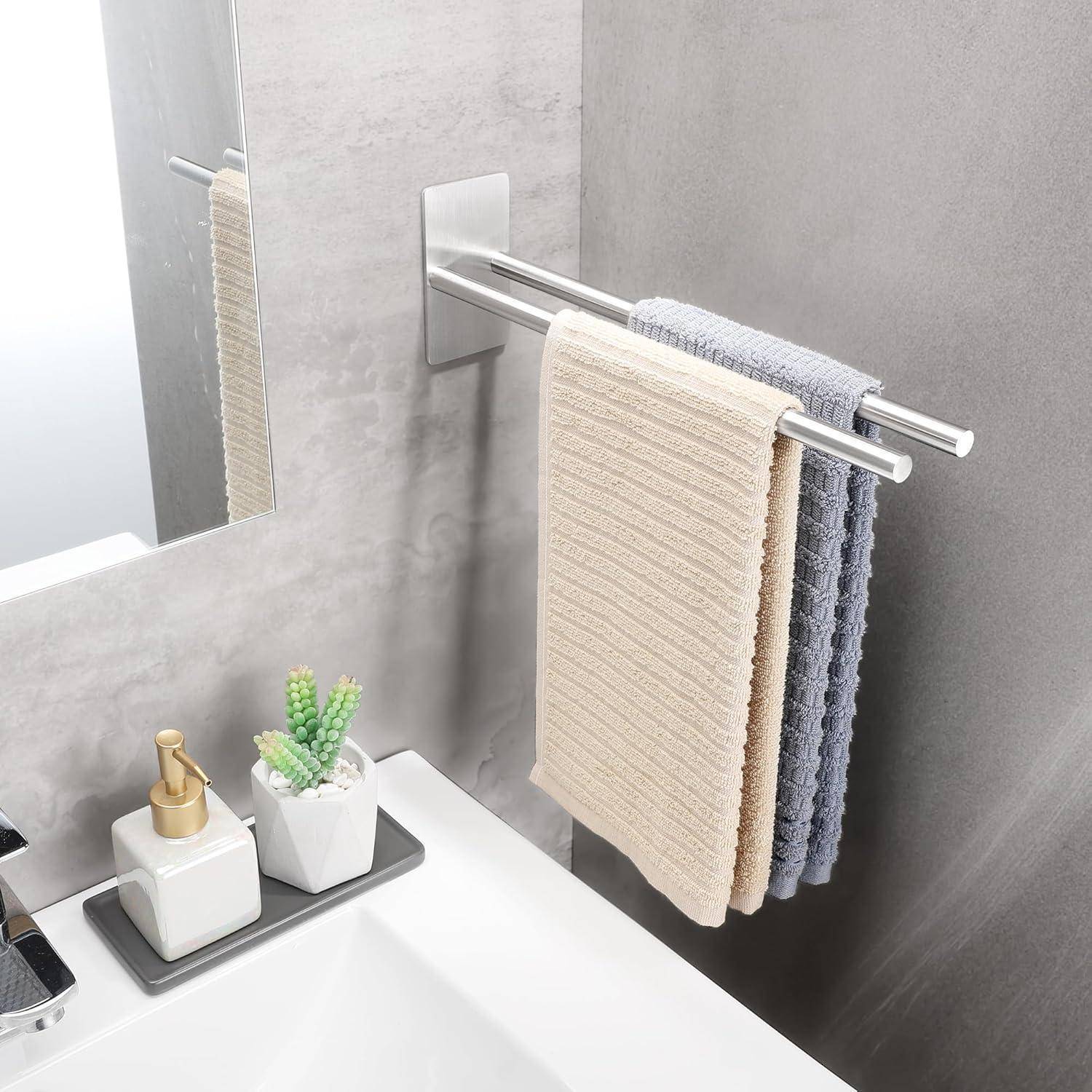 Ein modernes Badezimmer mit zwei Handtüchern, in Beige und Blau, die an einem eleganten Handtuchhalter hängen. Ein weißes Waschbecken ist mit einem Seifenspender und einer kleinen Pflanze geschmückt.