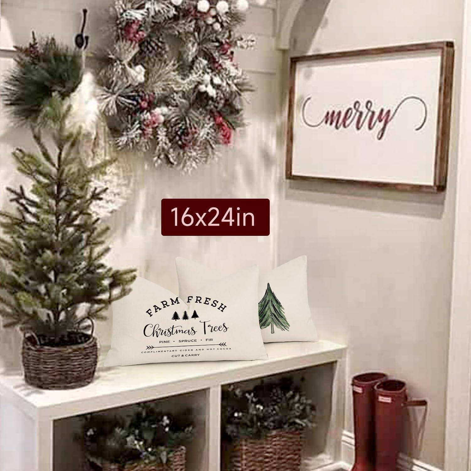 Ein weihnachtlich gestalteter Eingangsbereich mit einem kleinen geschmückten Baum, einem festlichen Kranz, Kissen mit Feiertagsmotiven und einem Schild mit der Aufschrift „fröhlich