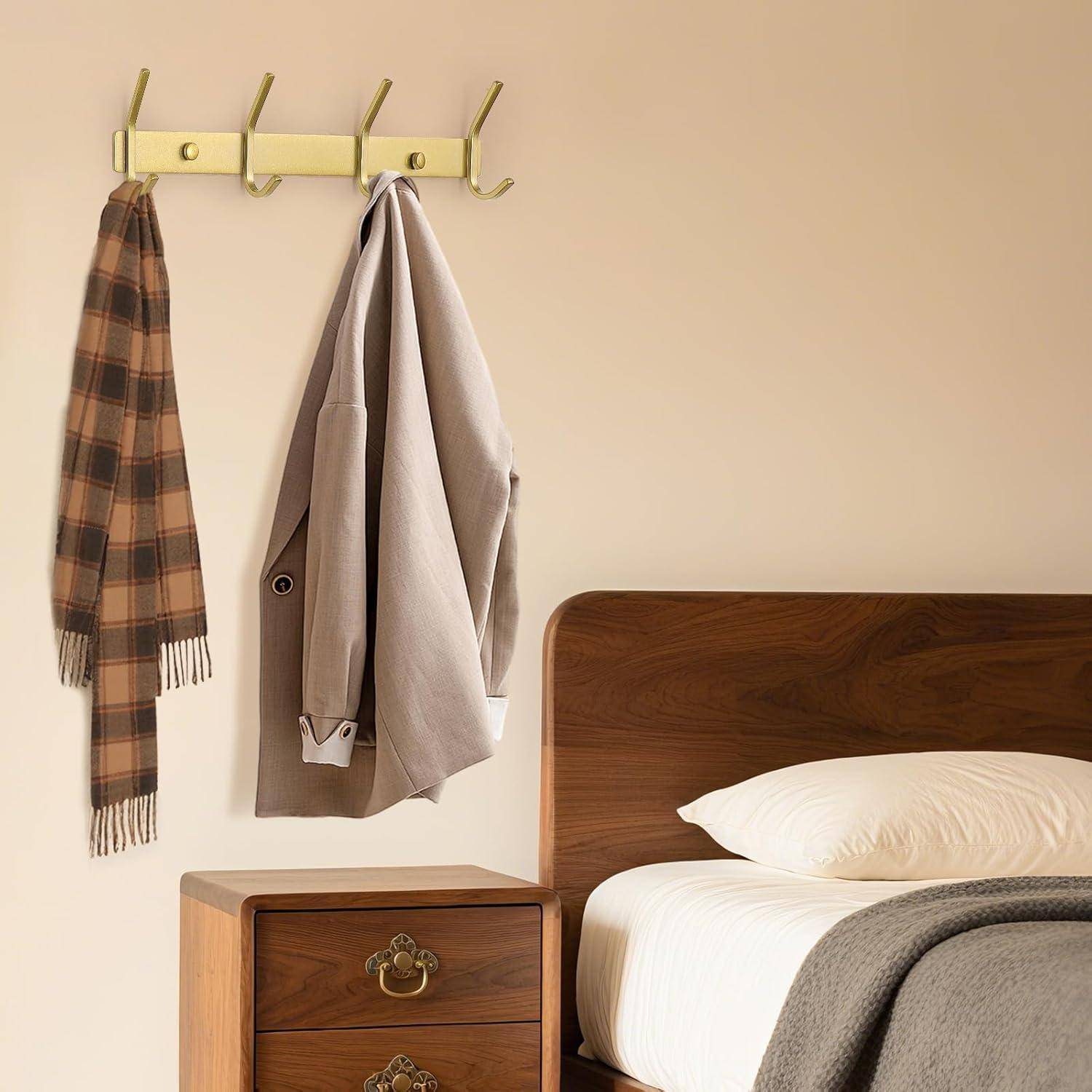 Ein Holzbett mit weißen Kissen, ein Nachttisch, eine Garderobe mit einer Jacke und einem kariertem Schal vor einer beigen Wand.
