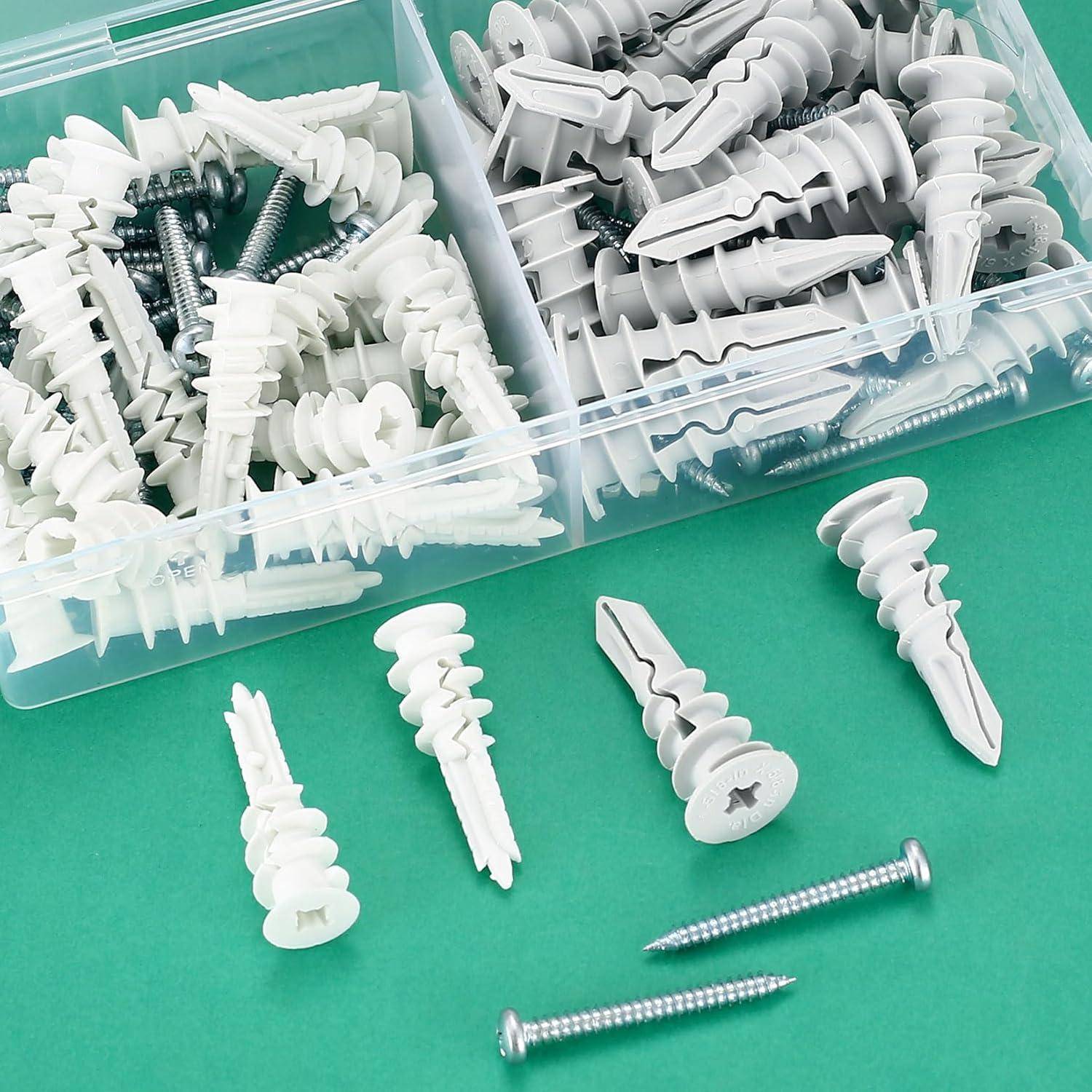 Eine Box, die in zwei Abschnitte geteilt ist, enthält weiße und graue Kunststoff-Dübel, mit mehreren silbernen Schrauben, die daneben auf einer grünen Oberfläche liegen.