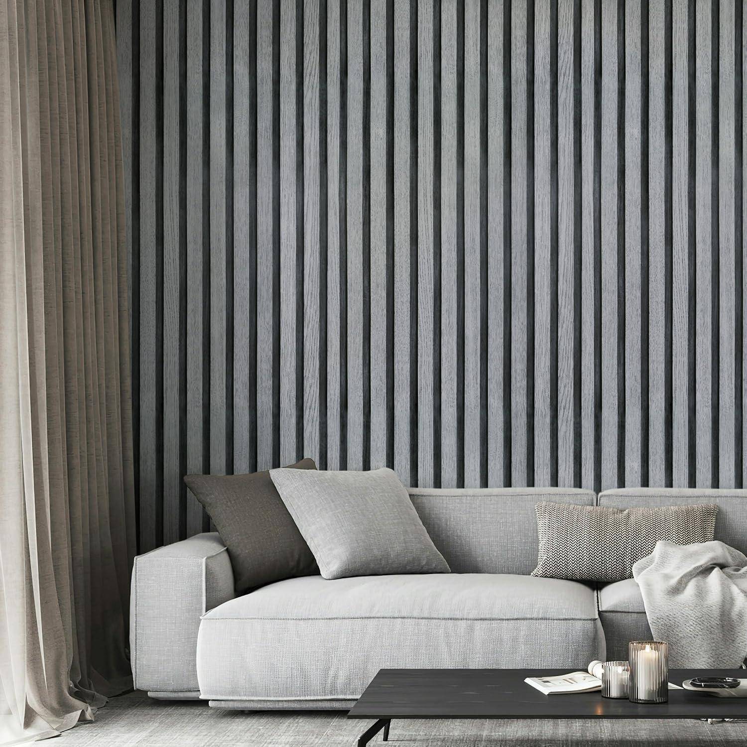 Ein moderner Wohnraum mit einem hellgrauen Sofa, das zwei Kissen trägt, einem schwarzen Couchtisch und vertikaler gestreifter Tapete, was einen minimalistischen Designstil andeutet.
