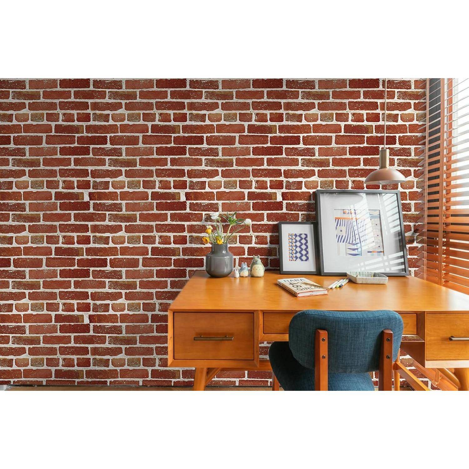 Ein hölzerner Schreibtisch mit einer Topfpflanze, Büchern und einem gerahmten Bild steht an einer Ziegelwand. Eine Pendelleuchte hängt darüber.