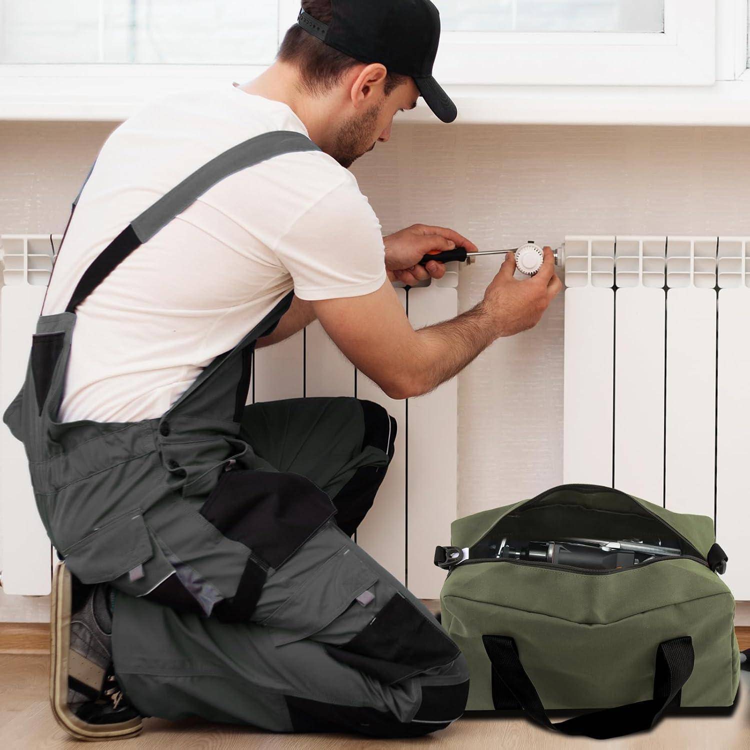 Ein Mann in Arbeitskleidung kniet neben einem Heizkörper und benutzt einen Schraubendreher. Eine Werkzeugtasche sitzt in der Nähe und deutet auf Wartungs- oder Reparaturarbeiten hin.