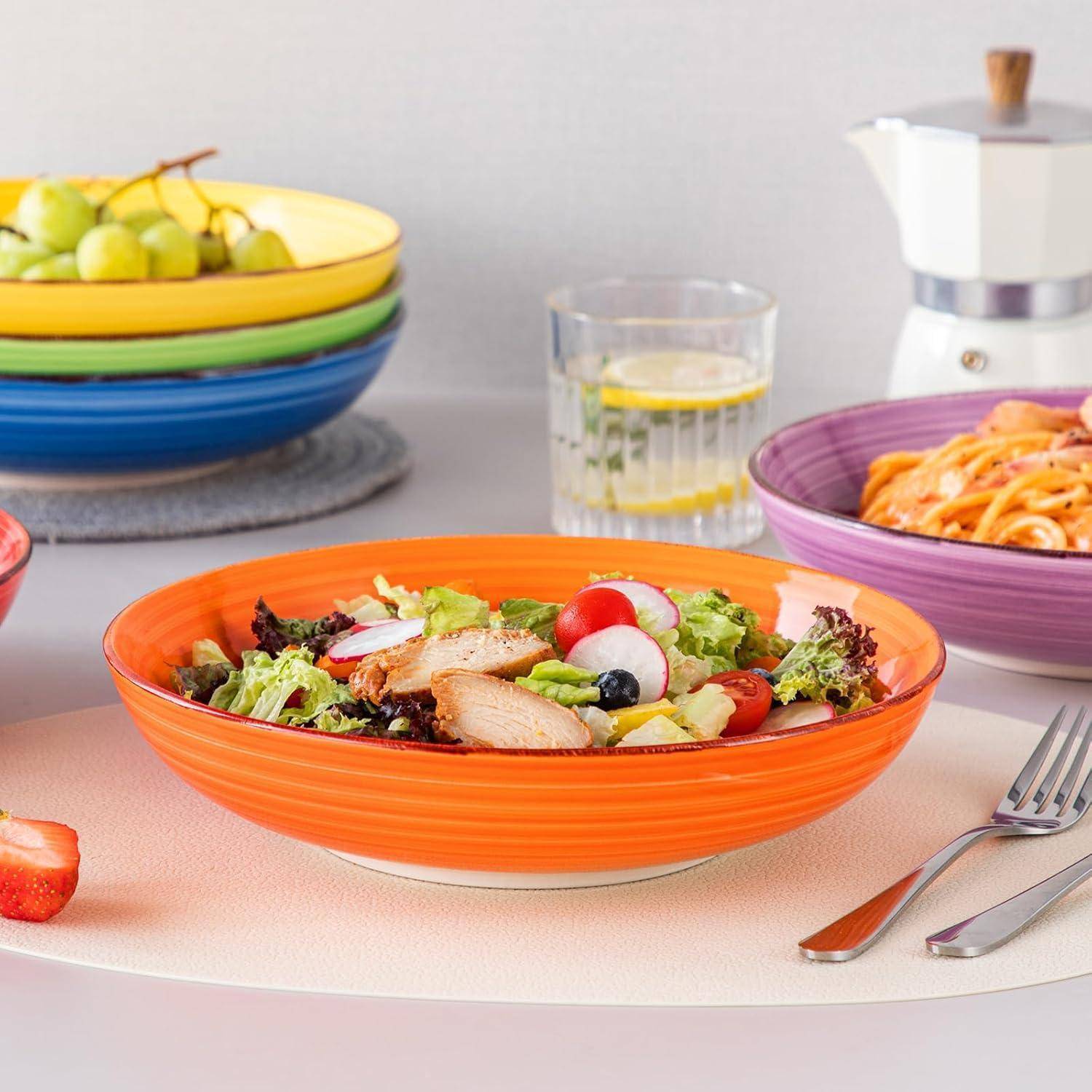 Ein bunter Salat mit Hühnchen und Gemüse in einer orangefarbenen Schüssel, platziert auf einem Esstisch, umgeben von verschiedenen Gerichten und einem Glas Zitronenwasser.