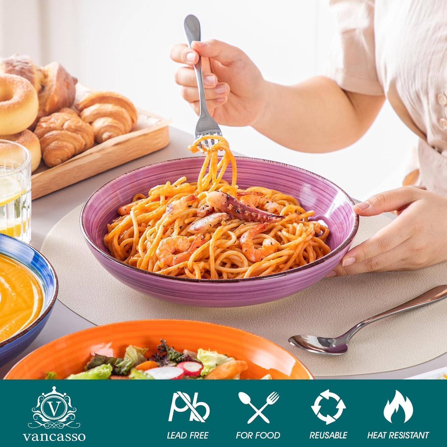 Person isst Spaghetti mit einer Gabel in einer lila Schüssel, umgeben von Brot, Salat und orangefarbener Suppe. Der Tisch hat ein Etikett mit der Aufschrift 
