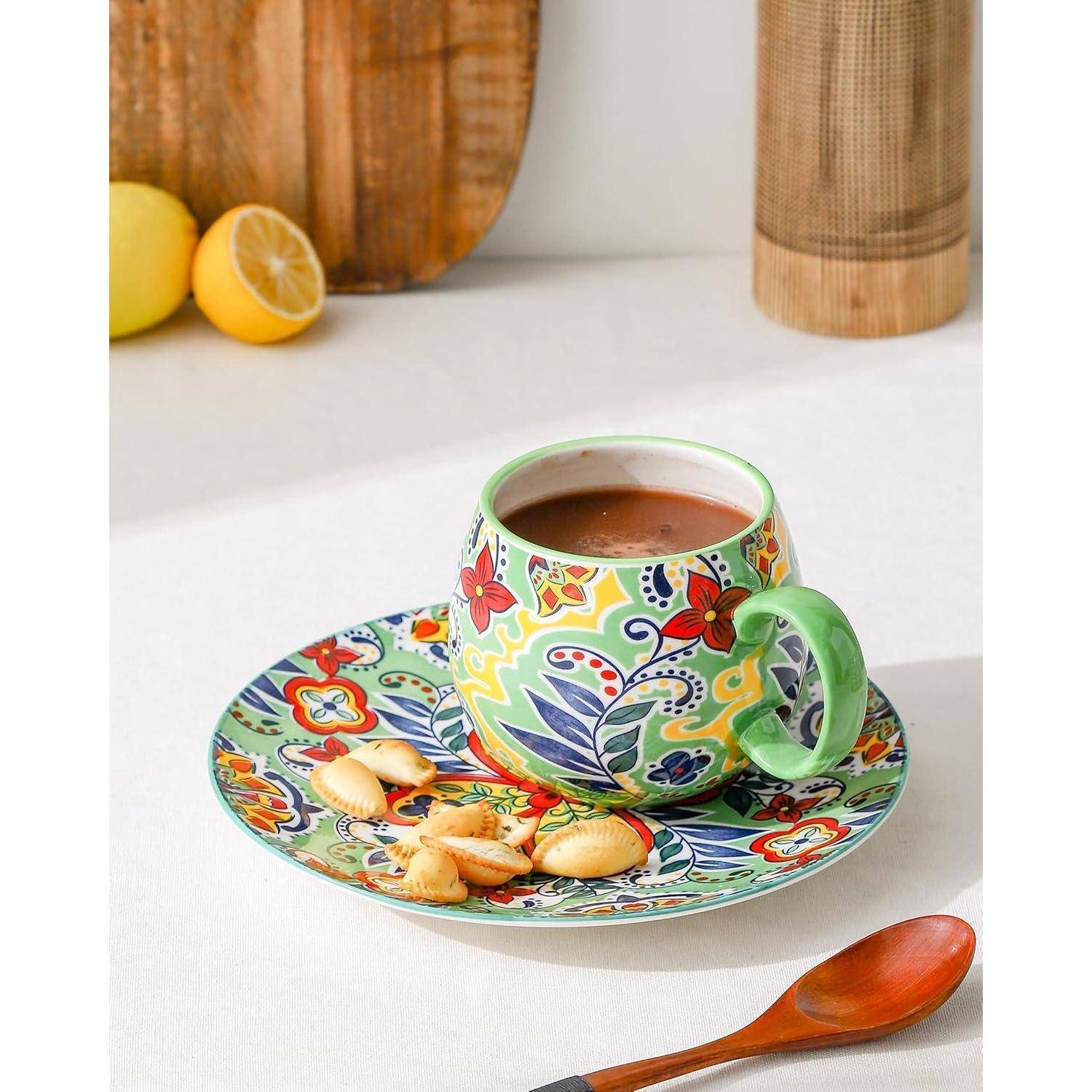 Eine farbenfroh gemusterte Tasse mit einem lebhaften Blumenmuster auf einer passenden Untertasse, gefüllt mit heißer Schokolade. In der Nähe liegen aufgeschnittene Zitrone und ein Holzlöffel.