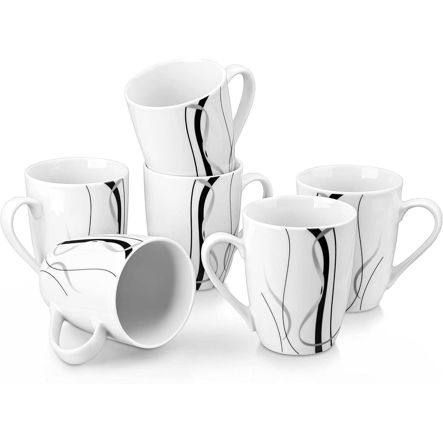 Sechs weiße Keramiktassen mit schwarzen abstrakten Linien, künstlerisch angeordnet, wobei eine Tasse auf der Seite liegt und ein modernes Küchengeschirr-Design darstellt.