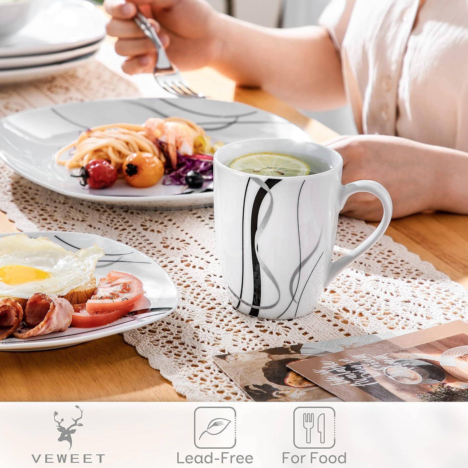 Eine Tischeindeckung mit einem Frühstück bestehend aus einem Spiegelei, Würstchen, Tomate und Pfannkuchen auf Tellern, dazu eine Tasse Tee.
