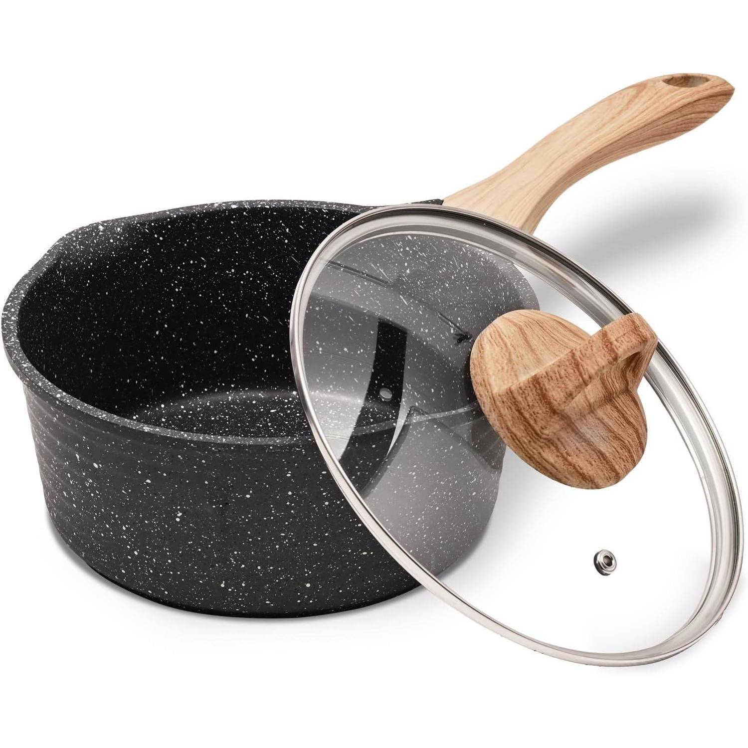 Ein schwarzer gefleckter Kochtopf mit einem Deckel und Holzgriff, zum Kochen gedacht, in einer Studiosituation. Der Deckel ist aus Glas mit einem Holzknauf.