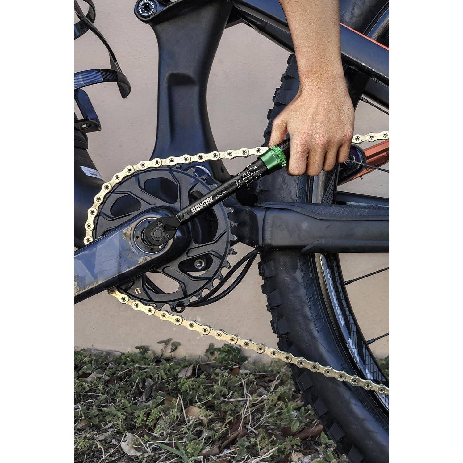 Eine Person spannt die Kette eines Mountainbikes mit einem T-Griff-Werkzeug. Das Fahrrad steht auf Gras, wobei der Fokus auf der Kette und dem Zahnkranz liegt.